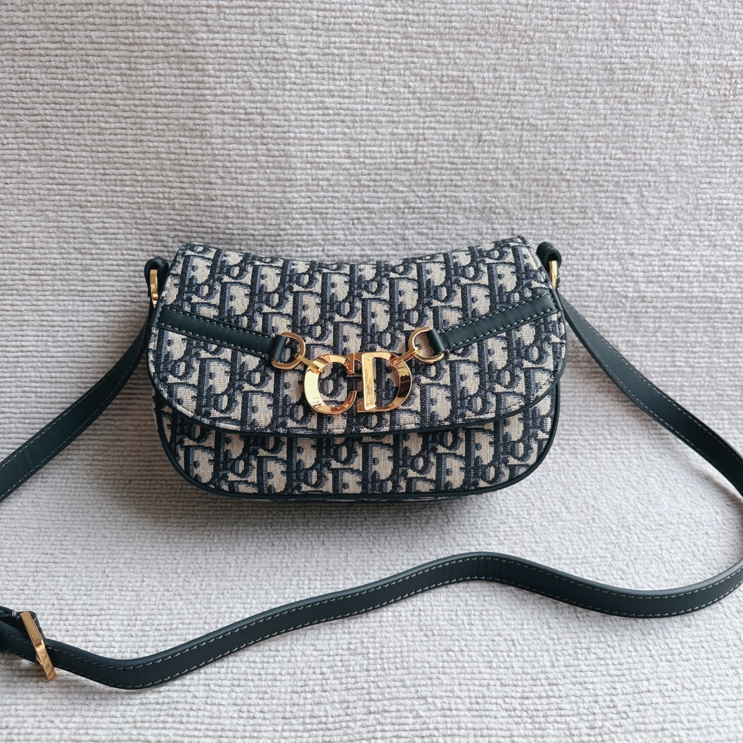 The Dior CD Besace Small Saddle Bag is crafted from Dior blue Oblique print fabric and features a striking metal CD logo with vintage gold finish