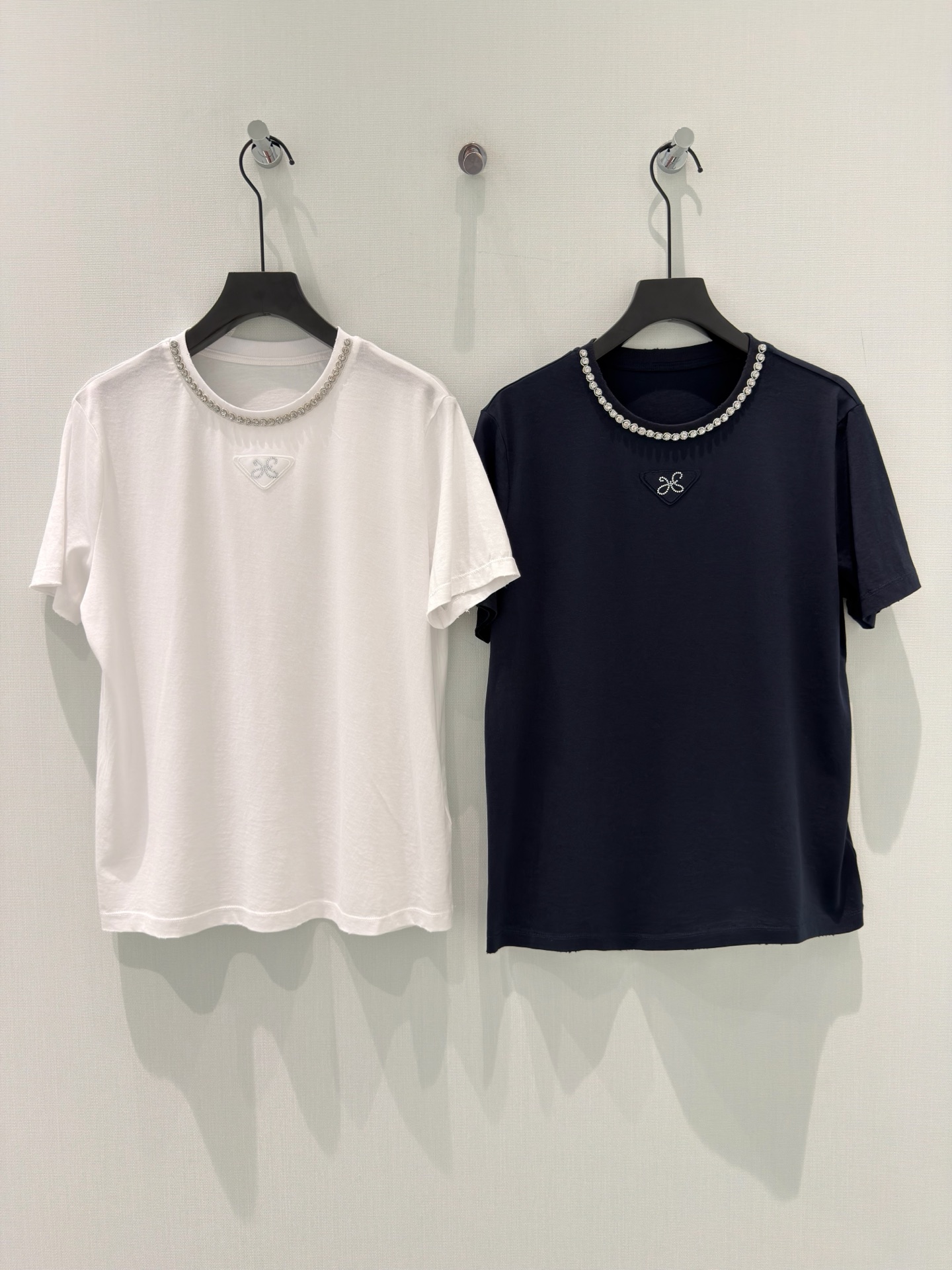 NO:833552,Designer [26 summer new pure cotton chest triangle embroidery logo diamond short-sleeved T-shirt loose top] This pure cotton diamond T-shirt is a gentle finishing touch for daily wear.  We select skin-friendly and breathable cotton fabric, which is as soft as a cloud and has comfortable and breathable properties. It bids farewell to the sultry and restrictive feeling, and is suitable for all seasons. A circle of exquisite rhinestones around the neckline injects agility and sparkle into simplicity, making it low-key yet refined. The triangle embroidered logo on the chest and the details highlight the texture, giving the basic T-shirt a light luxury style.  White and navy blue are available in two colors. Whether worn alone or layered, you can easily create a variety of styles such as refreshing commuting and casual outings. It is an indispensable and versatile treasure item in the wardrobe. S-L,, T-shirt, tees, t-shirt,19860909设计师【26夏季新款纯棉胸前三角刺绣标识镶钻短袖T恤宽松上衣】 这款纯棉镶钻T恤,是日常穿搭的温柔点睛之笔. 甄选亲肤透气的全棉面料,触感柔软如云,自带舒适透气属性,告别闷热束缚感,适配四季穿搭.领口一圈精致水钻,在简约中注入灵动闪耀,低调又不失精致感,胸前三角刺绣标识,细节处彰显质感,为基础款T恤赋予轻奢格调. 白与藏青双色可选,无论是单穿还是内搭,都能轻松打造清爽通勤、休闲出街等多种风格,是衣柜里不可或缺的百搭宝藏单品. S-L,,T-shirt,tees，t-shirt,,Women's clothing