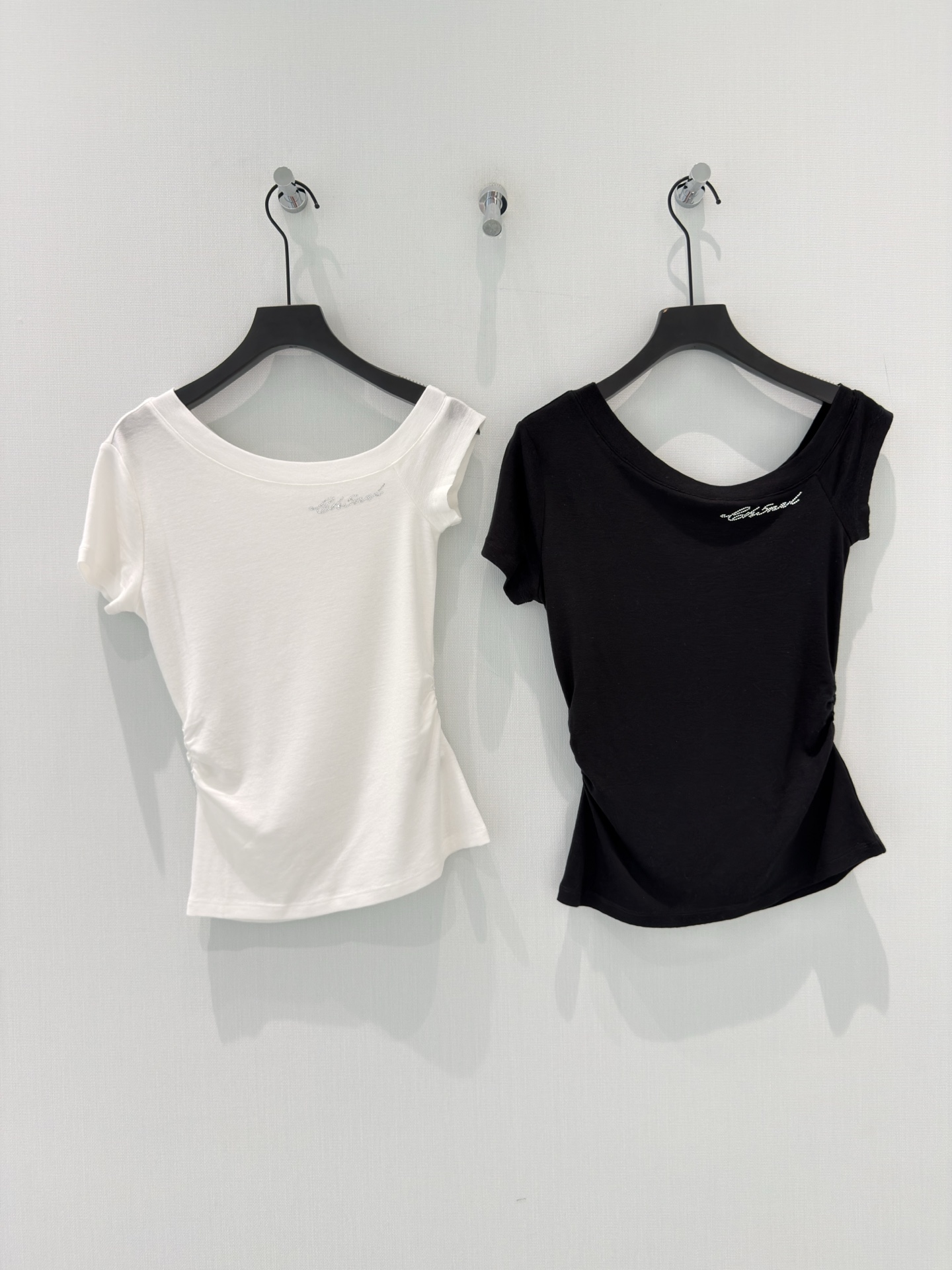 NO:861560,Chane* [26 new summer design, discreet off-shoulder one-line collar, hot-drilled letters, side waist twist, Tencel wool short-sleeved T-shirt slimming top] Using the light warmth of 76 Tencel's soft wool, it is woven with a soft and skin-friendly feel, and fits the body like a second layer of skin.  The trapezius muscle-friendly one-word collar quietly elongates the shoulder and neck lines; the side waist is twisted and cut to contain excess flesh and outline a gentle waist; the hot-drilled handwritten signature on the neckline is low-key and shimmering, and there is a hidden secret in simplicity. It is black and white and suitable for all bottoms in the wardrobe. It is refreshing and breathable when worn alone, and gentle and versatile when layered. It is an all-purpose model that cannot be separated from the spring and summer wardrobe. SML,,chanel,T-shirt,tees,t-shirt,19860909Chane*【26夏季新款设计小心机露肩一字领烫钻字母侧腰扭结天丝羊毛短袖T恤显瘦上衣】 以76天丝的柔润羊毛的轻暖,织就自带柔光的亲肤体感,像第二层肌肤般贴合身线. 斜方肌友好的一字领,悄悄拉长肩颈线条；侧腰扭结剪裁,收住多余肉肉,勾勒温柔腰型；领口的烫钻手写签名,低调闪着细碎光泽,简约中藏着小心机. 黑白两色,适配衣橱所有下装,单穿清爽透气,叠穿温柔百搭,是春夏衣橱里离不开的万能款. SML,,chanel,T-shirt,tees，t-shirt,,Women's clothing
