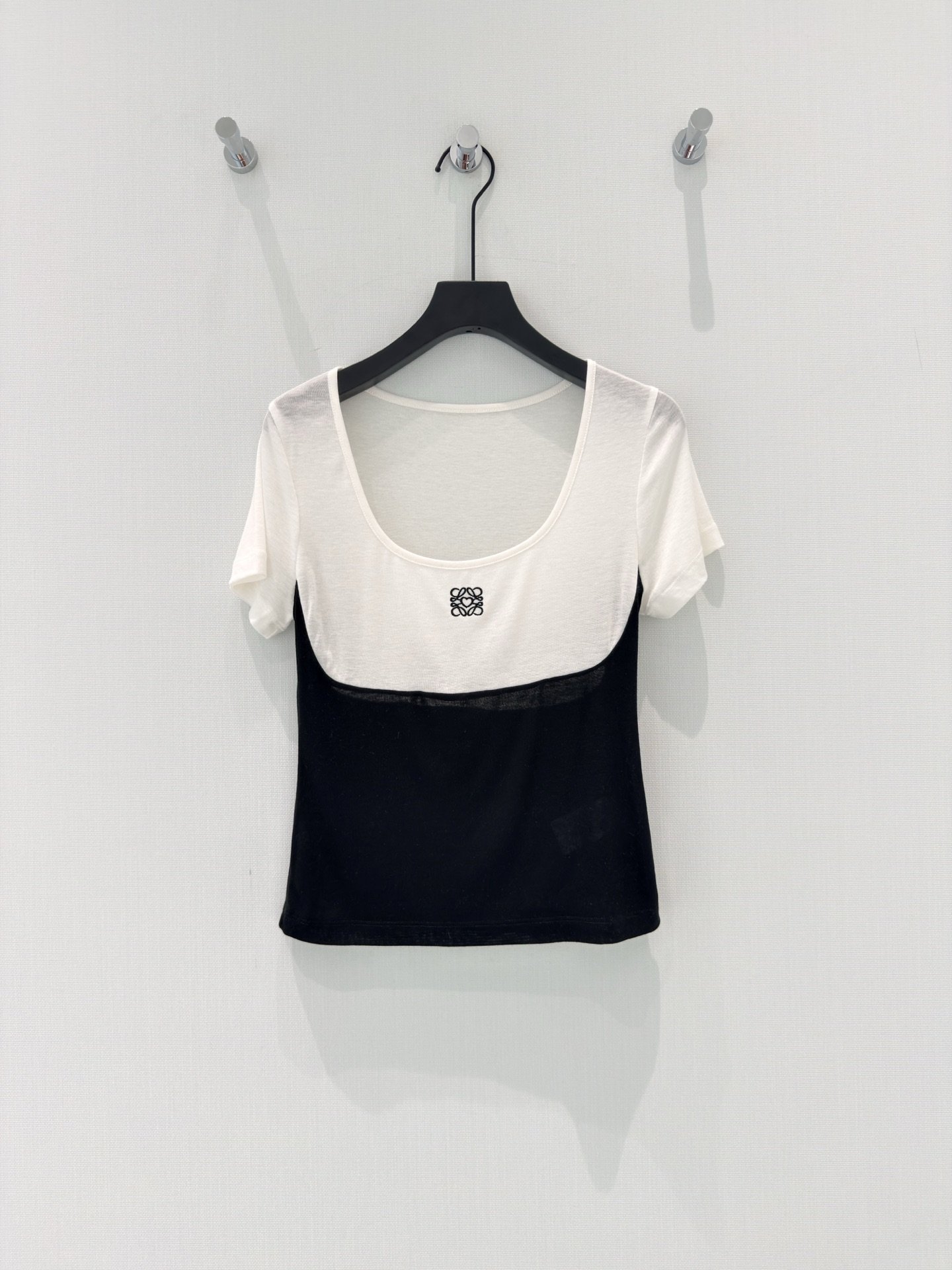 NO:875856,Loew* [26 summer new fashion classic black and white contrast U-shaped design front and back embroidery slimming short-sleeved T-shirt Lyocell wool top] 1. [Black and white atmosphere]  Classic black and white contrasting colors outline neat lines, with low-saturated tenderness and coolness intertwined. The U-shaped collar softly modifies the neckline, and the lyocell wool blended fabric has a clear and breathable feeling, is close-fitting but not stuffy, and comes with a soft focus filter. The iconic embroidery on the chest embellishes the details, and the letters on the back echo in a low-key manner. Simplicity hides ingenuity, making it easy to wear a high-end relaxed feeling. 2. [Everyday Versatility]  The basic model that is just needed in summer, but it hides full texture. The skin-friendly fabric of lyocell wool blend has a slightly hazy feeling, and the upper body is soft and breathable, suitable for all body shapes. The black and white splicing design weakens the body line, U-shaped collar + slim tailoring, paired with jeans for a casual street style, paired with a skirt for a gentle Korean feel, one piece unlocks multiple styles. 3. [Texture ceiling]  Rejecting the sameness of ordinary T-shirts, this black and white splicing style wins with details. The iconic embroidery + letter printing is low-key and recognizable; Lyocell + wool + spandex blend takes into account drape, elasticity and breathability, and is not easy to deform after long-term wear. The short version has optimized proportions, can be easily held for daily commuting and dating, and is versatile and durable. SML,,loewe,skirts,jeans,T-shirt,tees,t-shirt,19860909Loew*【26夏季新款时尚经典黑白撞色U型设计前后刺绣显瘦短袖T恤莱赛尔羊毛上衣】 1.【黑白氛围感】 经典黑白撞色勾勒利落线条,低饱和的温柔与酷感交织.U型领型柔和修饰颈线,莱赛尔羊毛混纺面料自带清透呼吸感,贴身不闷,自带柔焦滤镜.胸前标志性刺绣点缀细节,后背字母低调呼应,简约中暗藏巧思,轻松穿出高级松弛感. 2.【日常百搭款】 夏日刚需的基础款,却藏着满分质感.莱赛尔羊毛混纺的亲肤面料,自带微透朦胧感,上身软糯透气,适配所有身形.黑白拼接设计弱化身材线条,U型领+修身剪裁,搭配牛仔裤是随性街头风,配半裙又是温柔韩系感,一件解锁多种风格. 3.【质感天花板】 拒绝千篇一律的普通T恤,这件黑白拼接款用细节取胜.标志性刺绣+字母印花,低调中自带辨识度；莱赛尔+羊毛+氨纶混纺,兼顾垂坠感、弹力与透气性,久穿不易变形.短款版型优化比例,日常通勤、约会都能轻松hold住,百搭又耐看. SML,,loewe,skirts,jeans,T-shirt,tees，t-shirt,,Women's clothing