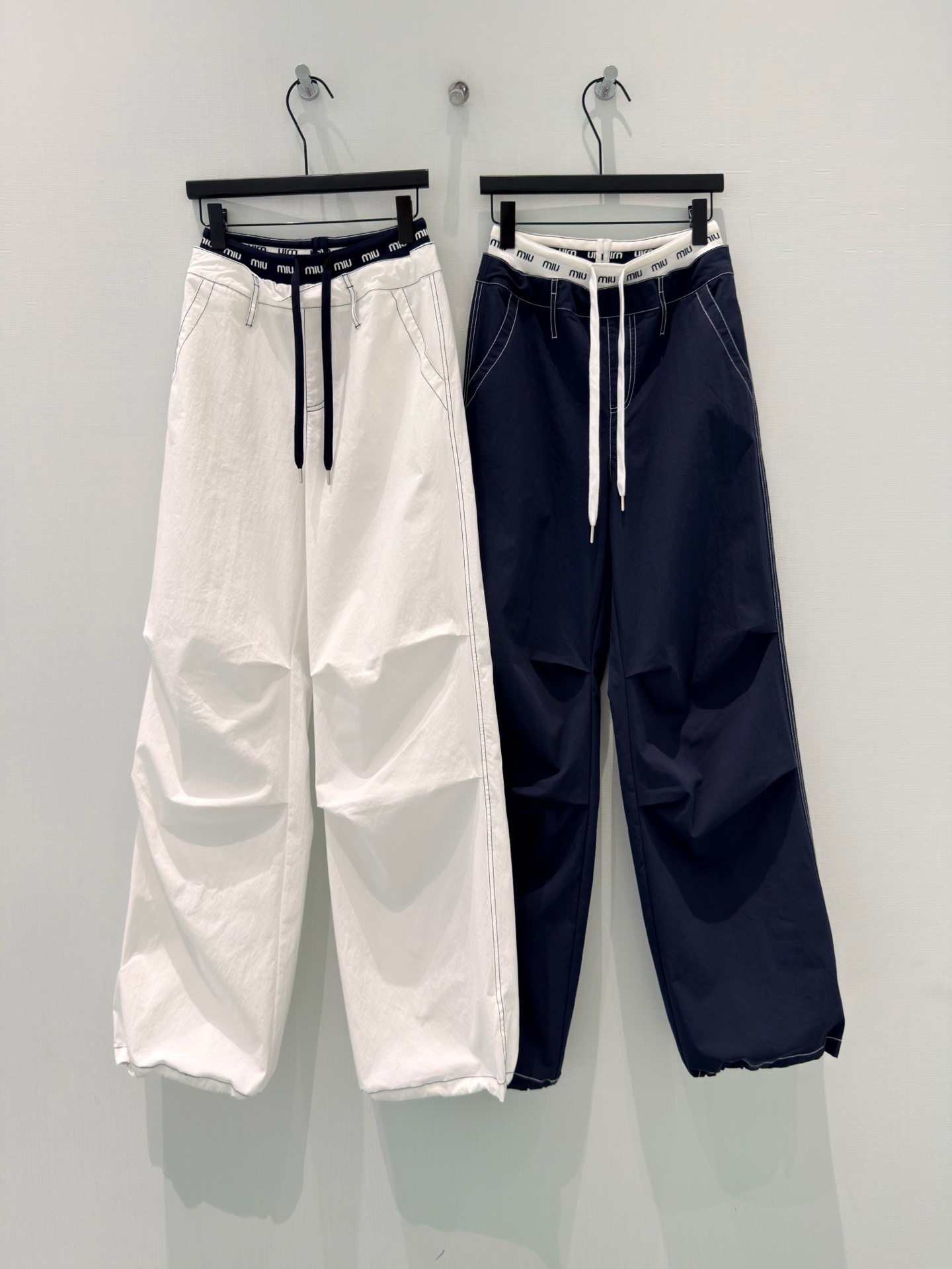 NO:877837,Miumi* [26 new summer style classic contrasting letter waist design heavy topstitch elastic waist drawstring workwear leggings]  6L5957 Miao style workwear trousers｜Contrasting letter waistband brings a light and luxurious atmosphere, available in off-white/navy blue. The topstitching is neat and delicate, the pleat design of the trousers body optimizes the fit, and the trouser legs can be drawstring.  Wear it and switch between wide legs or bound feet as you like. The cotton-nylon blended fabric is light and breathable, draped, anti-wrinkle and not sweaty, and the elastic drawstring waist does not pick up the waist. It is casual and fashionable for daily commuting and outings. It hides the flesh and looks slimming. Wear it loosely.  Classic m letter web waist casual overalls, contrasting waistband + same color drawstring, exquisite details. Heavy topstitching outlines the outline, three-dimensional pleating on the pants body to modify the leg shape, double pockets on the back waist are practical and beautiful. The fabric is made of cotton + nylon + spandex, soft and smooth, breathable and anti-wrinkle. The drawstring is hidden in the trouser legs, and it can be turned into legging overalls in seconds. The two ways of wearing are suitable for many scenes. Navy blue is calm, and off-white is refreshing, versatile with all kinds of T-shirts and shirts.  Wear two pants in one!  M-waist overalls, elastic waist that does not tighten the belly, folds in the trousers that hide a lot of fat, drawstrings at the trouser legs that can be widened or bunched, light and quick-drying fabrics are just right for spring and summer, white and navy blue are available in white and navy blue with your eyes closed!  SML,,miumiu,tees,t-shirt,19860909Miumi*【26夏季新款经典撞色字母腰头设计重工明线松紧腰抽绳工装束脚裤】 6L5957缪系工装束脚裤｜撞色字母腰头自带轻奢氛围感,米白/藏青双色任选.明线走线利落精致,裤身褶皱设计优化版型,裤脚可抽绳一裤两穿,阔腿/束脚随心切换.棉锦混纺面料轻薄透气,垂坠抗皱不闷汗,松紧抽绳腰不挑腰身,日常通勤、出游穿搭随性又时髦,藏肉显瘦拿捏松弛穿搭. 经典m字母织带腰休闲工装裤,撞色腰头+同色系抽绳,细节考究.重工明线辑边勾勒轮廓,裤身立体打褶修饰腿型,后腰双插袋实用美观.面料棉+锦纶+氨纶配比,软糯顺滑、透气抗皱,裤脚暗藏抽绳,秒变束脚工装裤,两种穿法适配多场景,藏青沉稳、米白清爽,百搭各类T恤小衫. 一裤两穿！m字母腰工装裤,松紧腰不勒肚子,裤身褶皱巨藏肉,裤脚抽绳可阔可束,轻薄速干面料春夏穿刚刚好,白、藏青两色闭眼入！ SML,,miumiu,tees，t-shirt,,Women's clothing