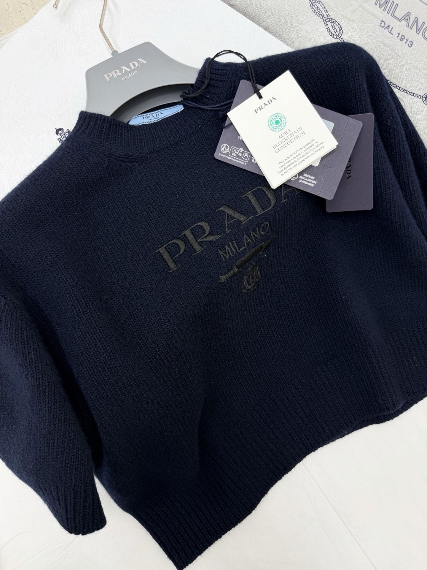 NO:799718,Original development, genuine real shot~~ 26ss navy blue logo embroidered sweater is made of soft cashmere and wool blend, super comfortable to wear!  The same color 'PRADA MILANO' embroidery + shield logo on the chest is low-key and recognizable. The short round neck design is OK to wear alone or layered. It can easily switch between daily and party styles. It is a must-have and versatile item in the wardrobe!  SML authentic details,,prada,19860909原版开发 正品实拍～～ 26ss 藏蓝色徽标刺绣针织衫采用柔软羊绒羊毛混纺,穿着超舒适！胸前同色系“PRADA MILANO”刺绣+盾形徽标,低调又有辨识度.短款圆领设计,单穿或叠搭都很OK,轻松切换日常和聚会风格,是衣橱必备百搭单品！SML 正品细节,,prada,,Women's clothing