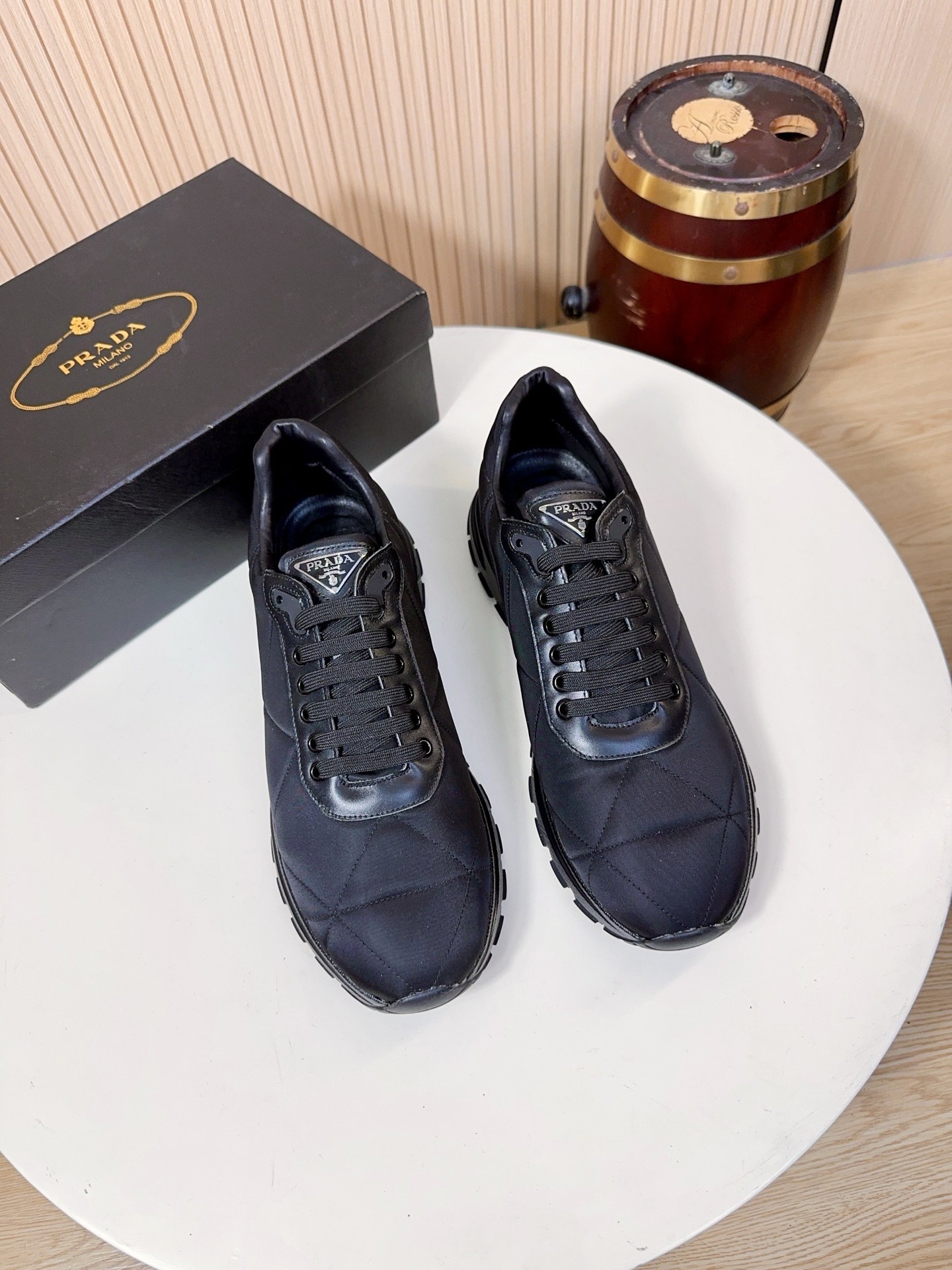 NO:833991,Prada is a top luxury brand founded in Milan, Italy in 1913. It subverts traditional avant-garde design and is recognized as a 'style definer' in the fashion industry. Prada's shoe series, especially sports shoes, has always been the benchmark for the high-end casual shoe market. (Shoe upper material Prada's iconic technical nylon)  The main body of the shoe is made of Prada's iconic Re-high-density technical mesh. This material is Prada's trump card material. It is lightweight, strong, breathable, waterproof and stain-resistant, and not easy to deform. It solves the problems of traditional leather shoes that are stuffy and difficult to care for. It is also one of the core features that distinguish Prada from other luxury brands.  The diamond quilting of the nylon fabric on the toe and side of the shoe is even and neat, and the leather and nylon splicing uses double-thread sewing technology, which improves the layering and wear resistance of the shoe body, and also neutralizes the technological sense of the nylon material, making the overall style more business-casual. The metal triangle logo on the tongue is the core identification element of Prada shoes. It has brand recognition in a low-key manner, and is also a favorite detail design of Prada fans.  The lining and insole are standard features of Prada's high-end shoes. The lining is mostly made of lambskin, which is soft against the skin and does not rub the feet. The tongue and mouth of the shoe are also thickened; the insole has the Prada hot-stamped logo, and some styles use memory foam + genuine leather foot pads. While cushioning and rebounding, it can fit the shape of the foot, and the feet will not be tired after walking for a long time.  The soles are made of Prada's custom-made non-slip rubber material, with the brand's iconic anti-skid pattern design, which has strong grip and is not easy to slip on rainy days. It has been lightweight, with a single shoe weighing only about 300g, which greatly reduces the burden on the feet; the midsole has a cushioning structure  , Some styles use Prada’s lightweight foam technology, which combines support and comfort, and is suitable for daily commuting and short-distance travel. 38-44, A9,, prada, prada, sneakers, sheepskin19860909Prada（普拉达）是1913年创立于意大利米兰的顶级奢侈品牌,以颠覆传统的先锋设计,是时尚界公认的“风格定义者”.Prada的鞋履系列,尤其是运动鞋,一直是高端休闲鞋市场的标杆.（鞋面材质Prada标志性科技尼龙）鞋身主体采用Prada标志性的Re-高密科技网布）,这种材质是Prada的王牌材质,兼具轻量化、强韧性与透气性,防水抗污、不易变形,解决了传统皮面鞋闷脚、难打理的问题,也是Prada区别于其他奢侈品牌的核心特征之一. 鞋头、鞋侧的尼龙面料的菱格绗缝走线均匀工整,皮革与尼龙的拼接处采用双线车缝工艺,提升了鞋身的层次感与耐磨性,也中和了尼龙材质的科技感,让整体风格更偏商务休闲.鞋舌上的金属三角标是Prada鞋履的核心识别元素,低调中自带品牌辨识度,也是Prada粉丝最爱的细节设计 内里与鞋垫Prada高端线鞋款的标配,内里多为羔羊皮,贴肤穿着柔软不磨脚,鞋舌、鞋口处也做了加厚处理；鞋垫带有Prada烫印标识,部分款式采用记忆棉+真皮垫脚,缓震回弹的同时,能贴合脚型,长时间走路也不累脚. 鞋底采用Prada定制的防滑橡胶材质,带有品牌标志性的防滑纹路设计,抓地力强,雨天也不易打滑；做了轻量化处理,单只鞋重量仅约300g,大幅减轻脚部负担；中底带有缓震结构,部分款式采用了Prada的轻量发泡科技,兼顾了支撑性与舒适感,适合日常通勤与短途出行.38-44,A9,,prada,prada,sneakers,sheepskin,Men's shoes