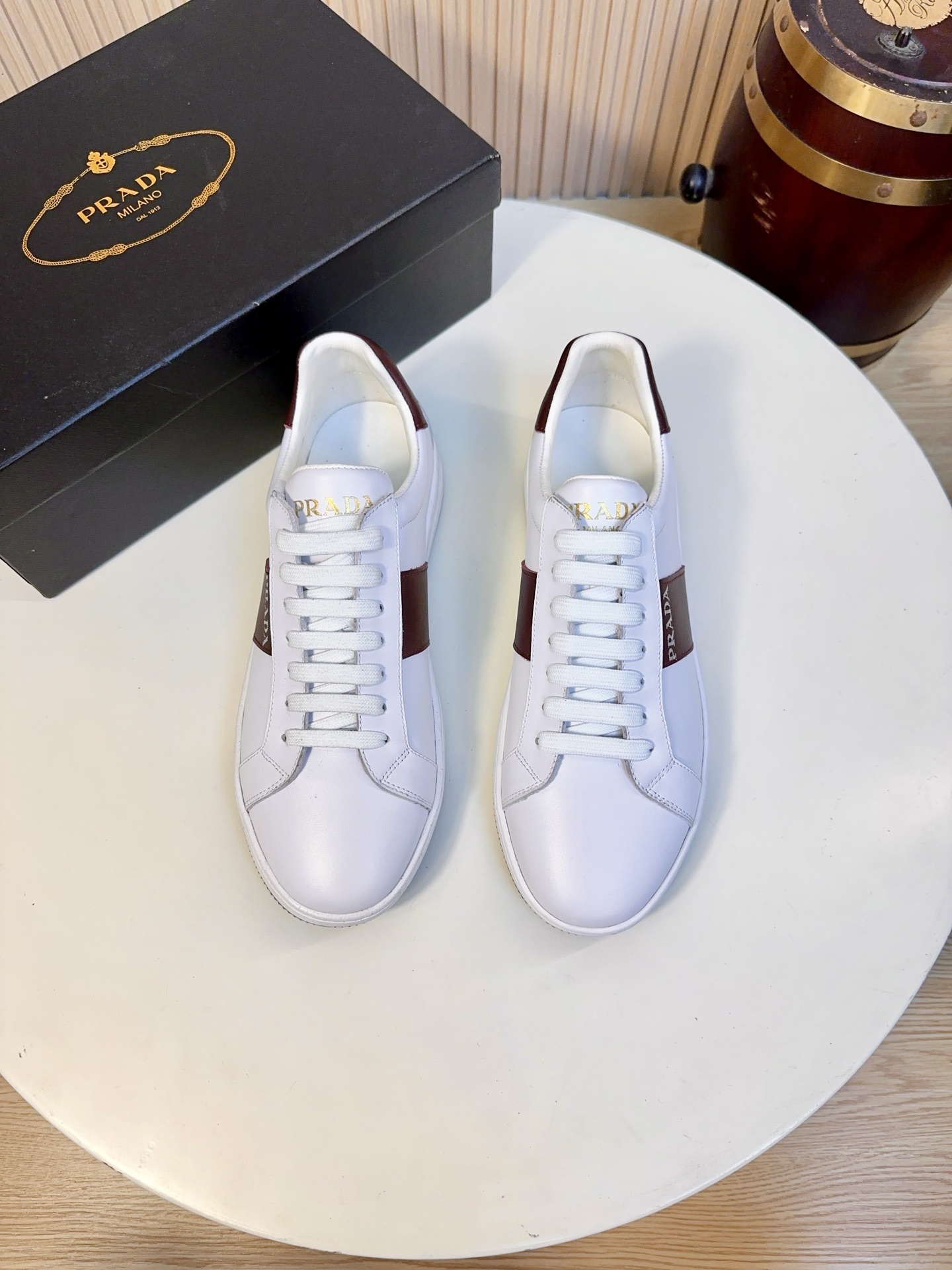 NO:833968,Prada is a top luxury brand founded in Milan, Italy in 1913. It subverts traditional avant-garde designs and is recognized as a 'style definer' in the fashion industry. Prada's shoe series, especially sports shoes, has always been the benchmark in the high-end casual shoe market.  The main body of the upper is made of imported first-layer calfskin, which is fine and soft, with a high-grade matte texture. It is not easy to wrinkle or crack. It can maintain the shape of the shoe for a long time. It is breathable and lightweight and will not feel stuffy in the summer. The burgundy webbing on the side is made of Prada's iconic webbing material and is printed with brand words, which is low-key and recognizable. The tongue/inner tongue is printed with hot stamping Prada.  Milano is written on the inside, and the inside is made of skin-friendly leather to reduce the feeling of friction; the removable leather insole is soft and supportive, and easy to clean. The sole is a lightweight non-slip rubber outsole, about 3.5cm thick, with a slight heightening effect and excellent cushioning performance, so you will not feel tired after walking for a long time; there is an embossed Prada logo on the side of the sole.  The mesh model with full brand details has an enamel triangle metal mark on the side, which is high-end but not cheap in texture; the side webbing and heel of the webbing model are contrasting with burgundy, which is Prada's classic 'low-key luxury' design language; the metal shoelace holes are polished smooth, without burrs and oxidation, and the texture and durability are online. 38-44, A9,, prada, prada, sneakers, cowhide19860909Prada（普拉达）是1913年创立于意大利米兰的顶级奢侈品牌,以颠覆传统的先锋设计,是时尚界公认的“风格定义者”.Prada的鞋履系列,尤其是运动鞋,一直是高端休闲鞋市场的标杆. 鞋面主体进口头层小牛皮,皮面细腻软糯,自带高级哑光质感,不易起皱、不易开裂,长期穿着也能保持鞋型挺括,兼顾透气与轻量化,夏天穿不闷脚. 侧边的酒红色织带款,采用Prada标志性织带材质,印有品牌字样,低调又有辨识度. 鞋舌/内里鞋舌印有烫金Prada Milano字样,内里采用亲肤皮革,减少磨脚感；可拆卸皮革鞋垫,柔软有支撑,方便清洁. 鞋底轻质防滑橡胶大底,厚度约3.5cm,自带轻微增高效果,缓震性能优秀,久走不累；鞋底侧面带有压花Prada徽标. 品牌细节拉满网面款侧面带有珐琅三角金属标,质感高级不廉价；织带款的侧边织带和后跟酒红色撞色,是Prada经典的“低调奢华”设计语言；金属鞋带孔打磨光滑,无毛刺、无氧化,质感和耐用性都在线.38-44,A9,,prada,prada,sneakers,cowhide,Men's shoes