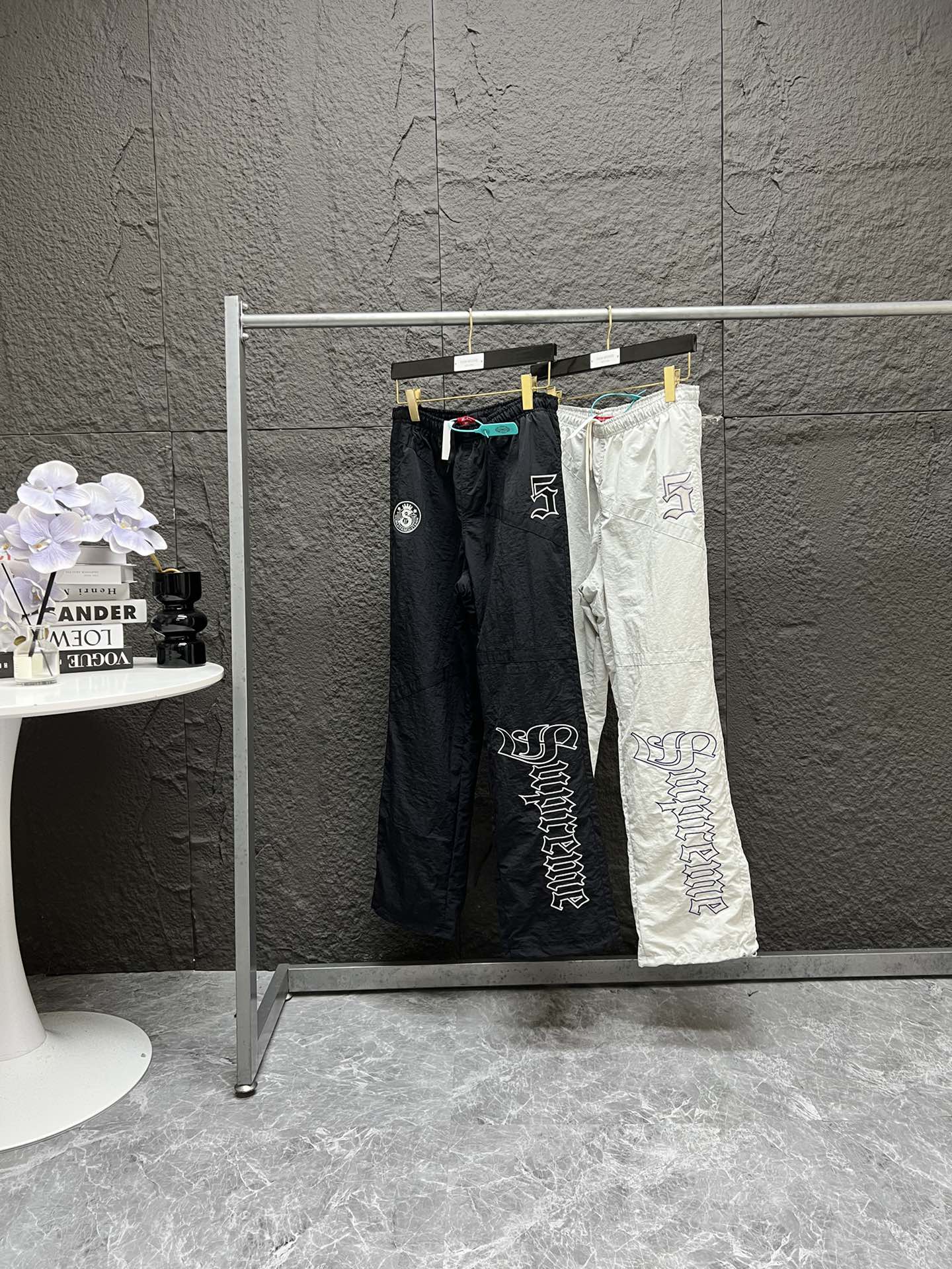 P220 顶级潮流套装 Supreme SS25 WEEK12 Old English Track Jacket 徽标图案贴花拉链开合立领美式潮流夹克外套 裤子 套装 男女同款 

-    颜色：灰白 黑色
-    尺码：S M L XL 
          【裤子尺码表】 
           S      M  	L	XL
裤长：104	  106  108	110
腰围：72-108	76-112	 80-116	84-120
臀围：	115	 119   123	127
裤口：	25	26	  26.8	27
强烈推荐搭配套装，原版购入开发，重工品质，大身超多刺绣logo标识，缜密细腻都是进口机器出货！！内里有网眼布，透气不贴身同时成本非常高！！整体大身拼接分割，衣身重工多处刺绣，同色系Ykk拉链丝滑无比！！全套配置辅料堆满，必须顶级品质！