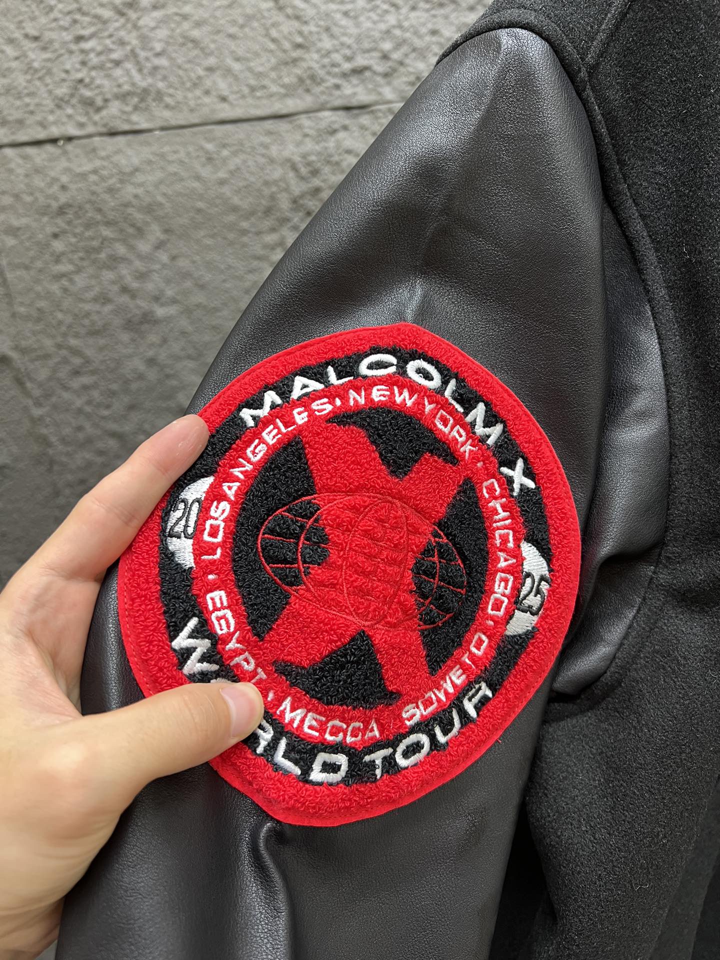 P280 原版复刻单品  Supreme x 40 Acres 联名款 SS25 WEEK9 Malcolm X Varsity Jacket 圆形毛绒徽标logo休闲美式潮流夹克 男女同款  宽松版型
颜色：黑色
尺码：S   M   L   XL
      胸围   衣长    肩宽    袖长
S:   142       70       60       62
M:  146       72       62       63
L:    150      74      63.5     64
xL:  154      76      64.5     65

今年的全系列热门单品，今天带来秋冬季节夹克外套！！大身毛呢面料，袖子皮料为进口皮料整体有皮质感同时哑光效果！！下摆领口袖口都有加密螺纹！！胸口品牌Sup缜密小刺绣，左侧又点缀40联名毛巾绣！！后背超大X刺绣logo！！主标领标都是定制带联名logo！！内里菱形格填充棉，秋冬季节足够！！十星⭐狠货，强烈推荐✔️✔️✔️