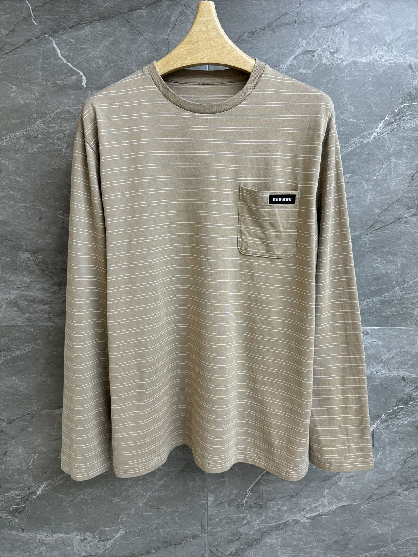 NO:310064,New early spring model is available. Miu striped long-sleeved T-shirt 2025 early spring series. Round neckline design. Pocket logo logo decoration embellishment. Striped contrasting color retro fashionable. Imported pure cotton fabric. Light, comfortable and breathable. Loose style. Slim and versatile. Full trademark. Size SML,,miumiu,tees, t-shirt,alexander wang.19860909早春新款上新啦 Miu条纹长袖T恤 2025早春系列 圆领领口设计 口袋logo徽标装饰点缀 条纹撞色复古时髦 进口纯棉面料 轻薄舒适透气 宽松版型 上身显瘦又百搭 商标齐全 尺码SML,,miumiu,tees，t-shirt,alexander wang,Women's clothing