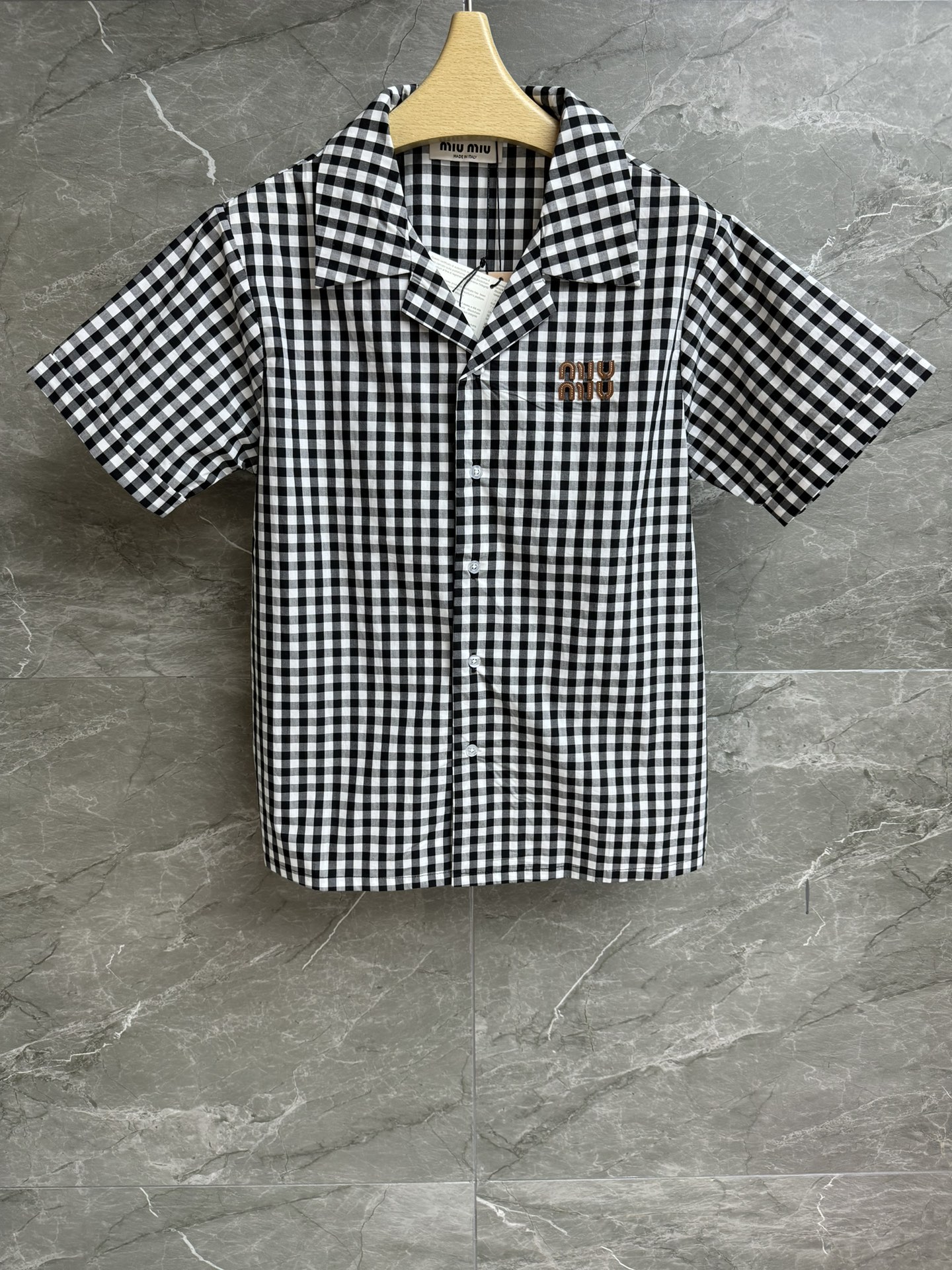 NO:432446,New summer models are available. Miu checked short-sleeved shirt. 2025 summer series. Lapel neckline design. Leather letter logo embroidery embroidery. Black and white check pattern. Casual retro and fashionable. Custom fabrics are light and comfortable. Loose style. Slim and versatile. Full trademark. Size SML,,miumiu,shirts,T-shirt,alexander wang.19860909夏季新款上新啦 Miu格纹短袖衬衫 2025夏季系列 翻领领口设计 皮革字母徽标刺绣点缀 黑白格纹图案 休闲复古时髦 定制面料轻盈舒适 宽松版型 上身显瘦又百搭 商标齐全 尺码SML,,miumiu,shirts,T-shirt,alexander wang,Women's clothing