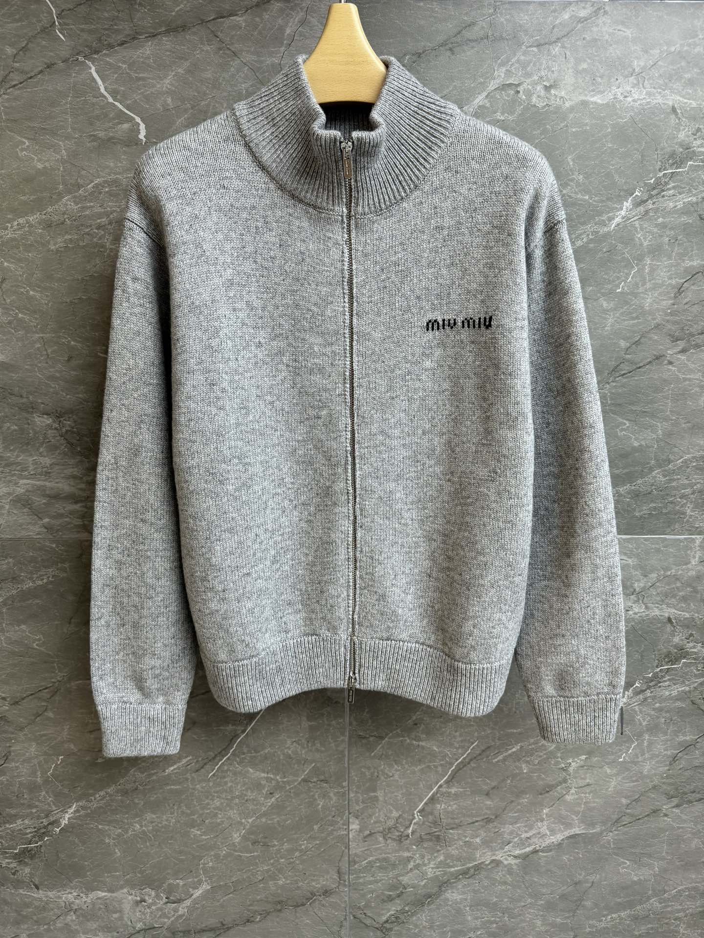 NO:685250,The new style for early spring is new. Miu gray wool cardigan 2026 early spring series. Stand collar zipper design. Letter logo intarsia embellishment on the chest. Gray color matching is high-end and fashionable. Wool knitted fabric. Normal fit. The upper body is slim and elegant. Complete trademarks. Sizes: smL,,miumiu,19860909早春新款上新啦 Miu灰色羊毛开衫 2026早春系列 立领拉链设计 胸前字母logo嵌花点缀 灰色配色高级时髦 羊毛针织面料 正常版型 上身显瘦又气质 商标齐全 尺码smL,,miumiu,,Women's clothing