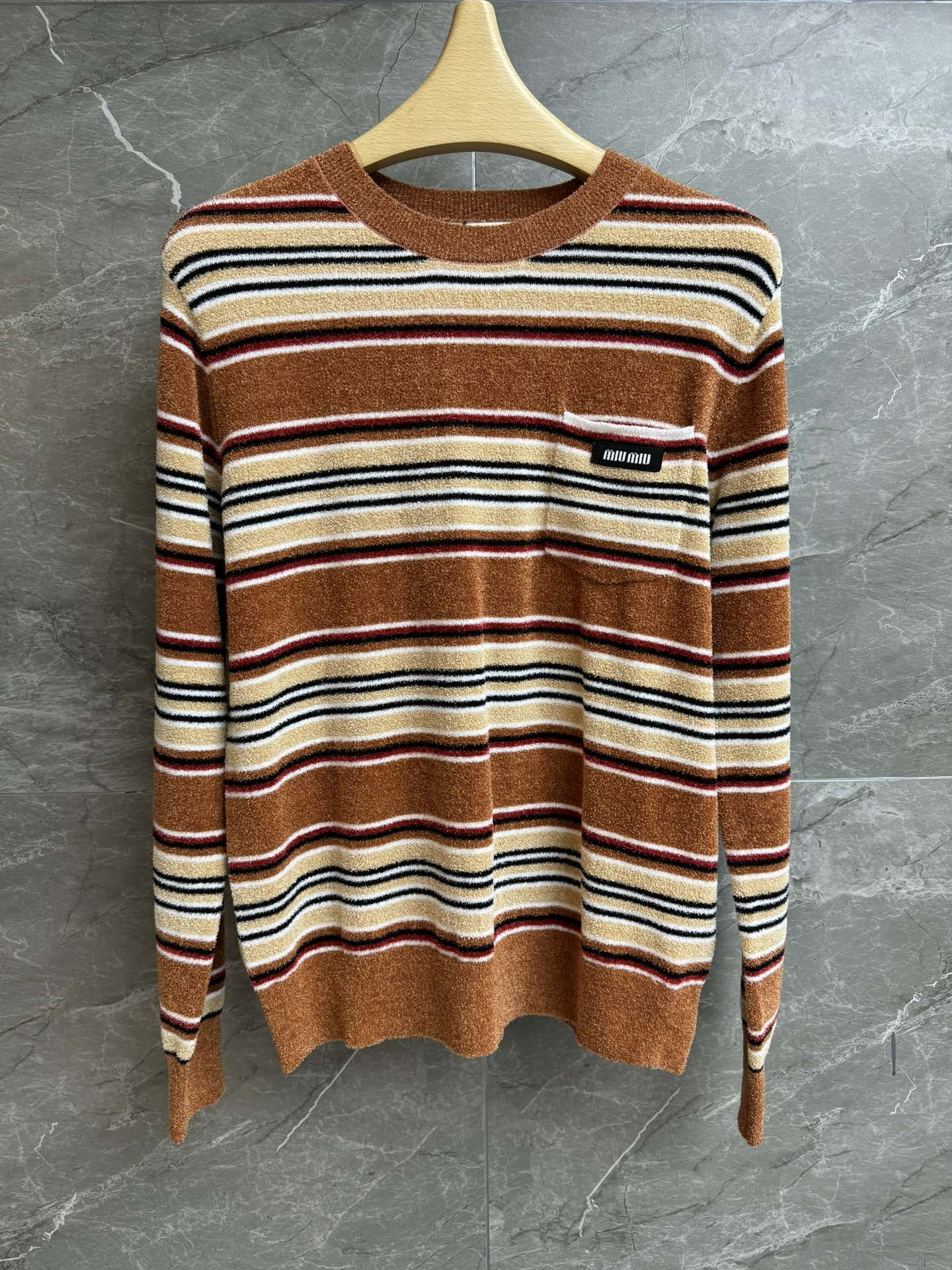 NO:710343,New style for early spring. Miu striped knit top 2026 early spring series. Round neck design. Letter logo patch embroidery embellishes pockets. Striped color matching is retro and fashionable. Circle yarn towel fabric. Soft and comfortable. Loose fit. The upper body is slim and versatile. Complete trademarks. Sizes SML,,miumiu,19860909早春新款上新啦 Miu条纹针织上衣 2026早春系列 圆领领口设计 字母logo贴布刺绣点缀口袋 条纹配色复古时髦 圈圈纱线毛巾面料 软糯舒适 宽松版型 上身显瘦又百搭 商标齐全 尺码SML,,miumiu,,Women's clothing