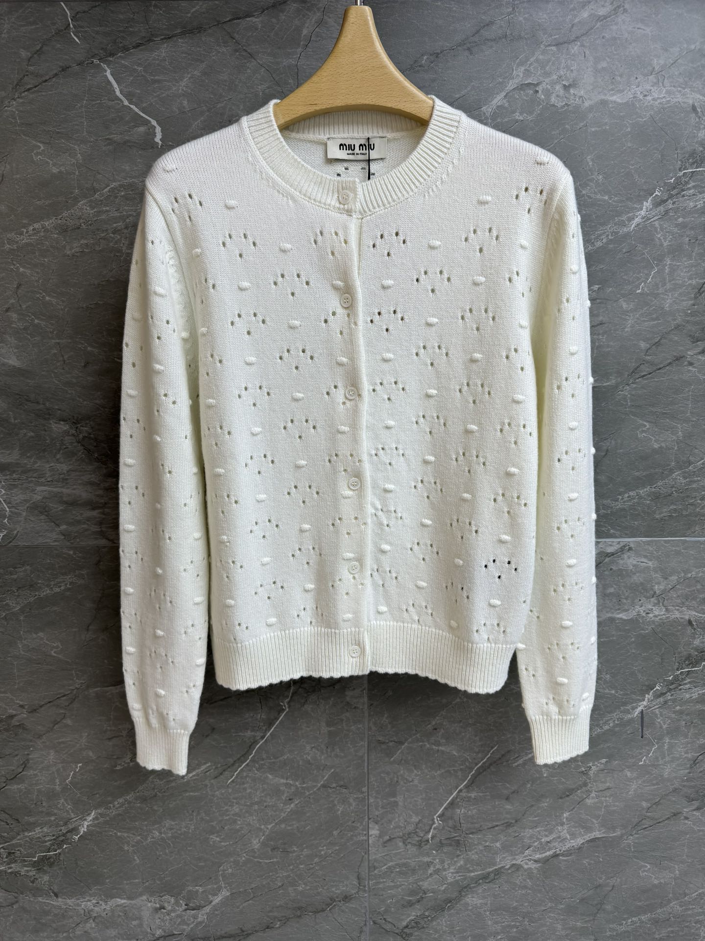 NO:738069,The new model for early spring has been shipped. Miu white hollow cardigan 2026 early spring series. Round neck single-breasted design. Logo embellishment on the back. Unique hollow hole craftsmanship. Fashionable and age-reducing. Wool knitted fabric. Light and comfortable. Slim fit. The upper body is slim and elegant. Complete trademarks. Sizes SML,,miumiu,19860909早春新款出货啦 Miu白色镂空开衫 2026早春系列 圆领单排扣设计 后背logo徽标点缀 别致的镂空挑孔工艺 时髦减龄 羊毛针织面料 轻薄舒适 修身版型 上身显瘦又气质 商标齐全 尺码SML,,miumiu,,Women's clothing