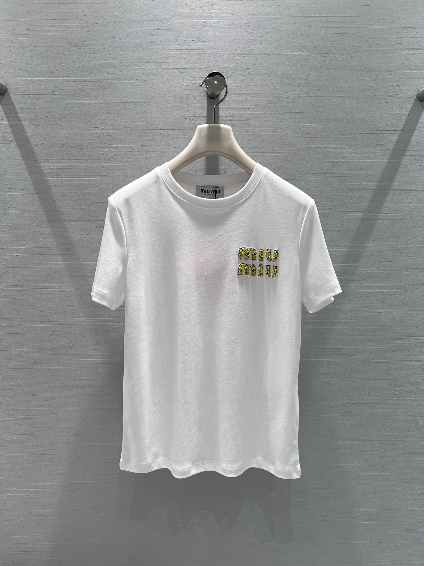 NO:686368,Support exchange MIU*26SS new spring and summer series // miu short-sleeved T-shirt with diamond letters. Made of high-quality cotton fabric, soft to the touch and skin-friendly, with good breathability. The chest is decorated with gold letters with diamond letters. The diamond decorations have strong luster and strong inlay, adding a sense of light luxury and sophistication to the basic T-shirt. The black and white solid color base ensures the versatility of the match and can be easily integrated into various styles. SML real shot details, miumiu, T-shirt, tees, t-shirt,19860909支持换款MIU*26SS春夏新品系列//miu系字母钉钻短袖T恤 优质棉质面料,触感柔软亲肤,透气性佳,胸前点缀金色钉钻字母装饰,钻饰光泽感强、镶嵌牢固,为基础款T恤增添了轻奢精致感,黑白纯色基底则保证了搭配的百搭性,轻松融入各种穿搭风格.SML实拍细节,,miumiu,T-shirt,tees，t-shirt,,Women's clothing