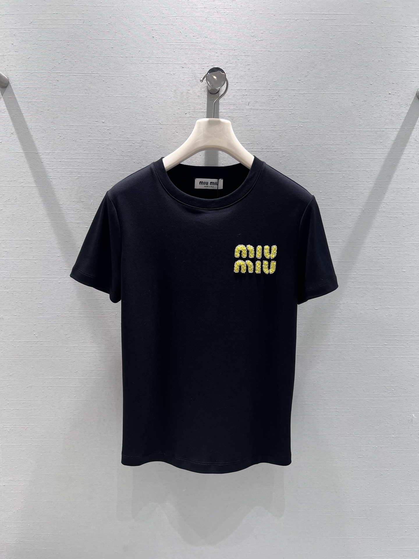 NO:686362,Support exchange MIU*26SS new spring and summer series // miu short-sleeved T-shirt with diamond letters. Made of high-quality cotton fabric, soft to the touch and skin-friendly, with good breathability. The chest is decorated with gold letters with diamond letters. The diamond decorations have strong luster and strong inlay, adding a sense of light luxury and sophistication to the basic T-shirt. The black and white solid color base ensures the versatility of the match and can be easily integrated into various styles. SML real shot details, miumiu, T-shirt, tees, t-shirt,19860909支持换款MIU*26SS春夏新品系列//miu系字母钉钻短袖T恤 优质棉质面料,触感柔软亲肤,透气性佳,胸前点缀金色钉钻字母装饰,钻饰光泽感强、镶嵌牢固,为基础款T恤增添了轻奢精致感,黑白纯色基底则保证了搭配的百搭性,轻松融入各种穿搭风格.SML实拍细节,,miumiu,T-shirt,tees，t-shirt,,Women's clothing