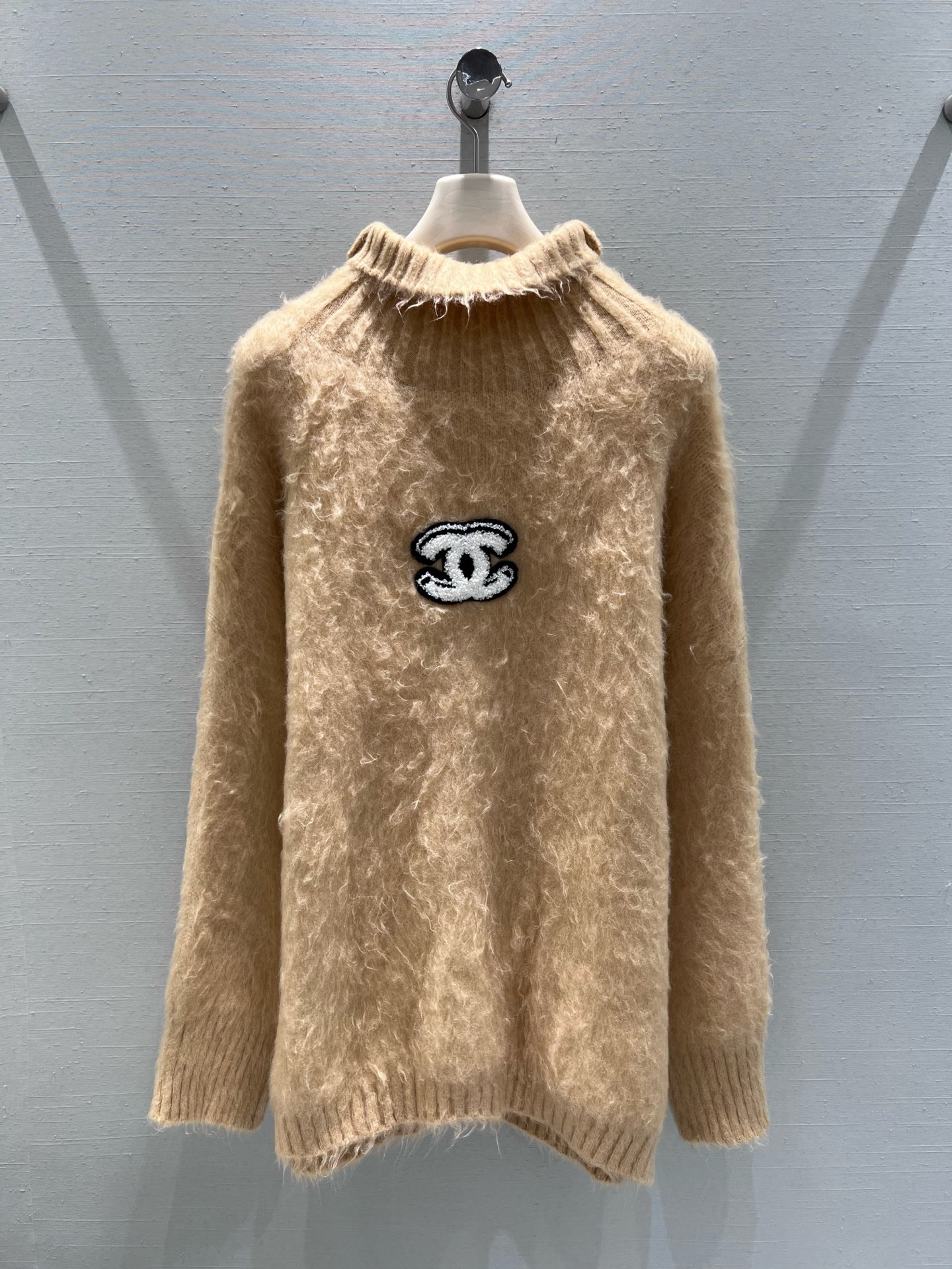 NO:695321,Support exchange Chan*L 2026SS early spring new product series // The camel sweater is made of soft and waxy plush fabric, with a gentle fluffy feel. The upper body is skin-friendly and warm. The collar adopts a slightly high collar raw edge design to add a casual retro accent; the body is embellished with classic double C embroidery patches, cleverly integrating light and luxurious fragrance elements with a sense of leisure. SML real shot details,, chanel,19860909支持换款Chan*L 2026SS早春新品系列//驼色针织衫软糯的毛绒面料,自带温柔的蓬松感,上身亲肤又保暖,领口采用微高领的毛边设计增添了随性的复古腔调；衣身点缀经典双C刺绣贴标,将轻奢的香风元素与休闲感巧妙融合.SML实拍细节,,chanel,,Women's clothing