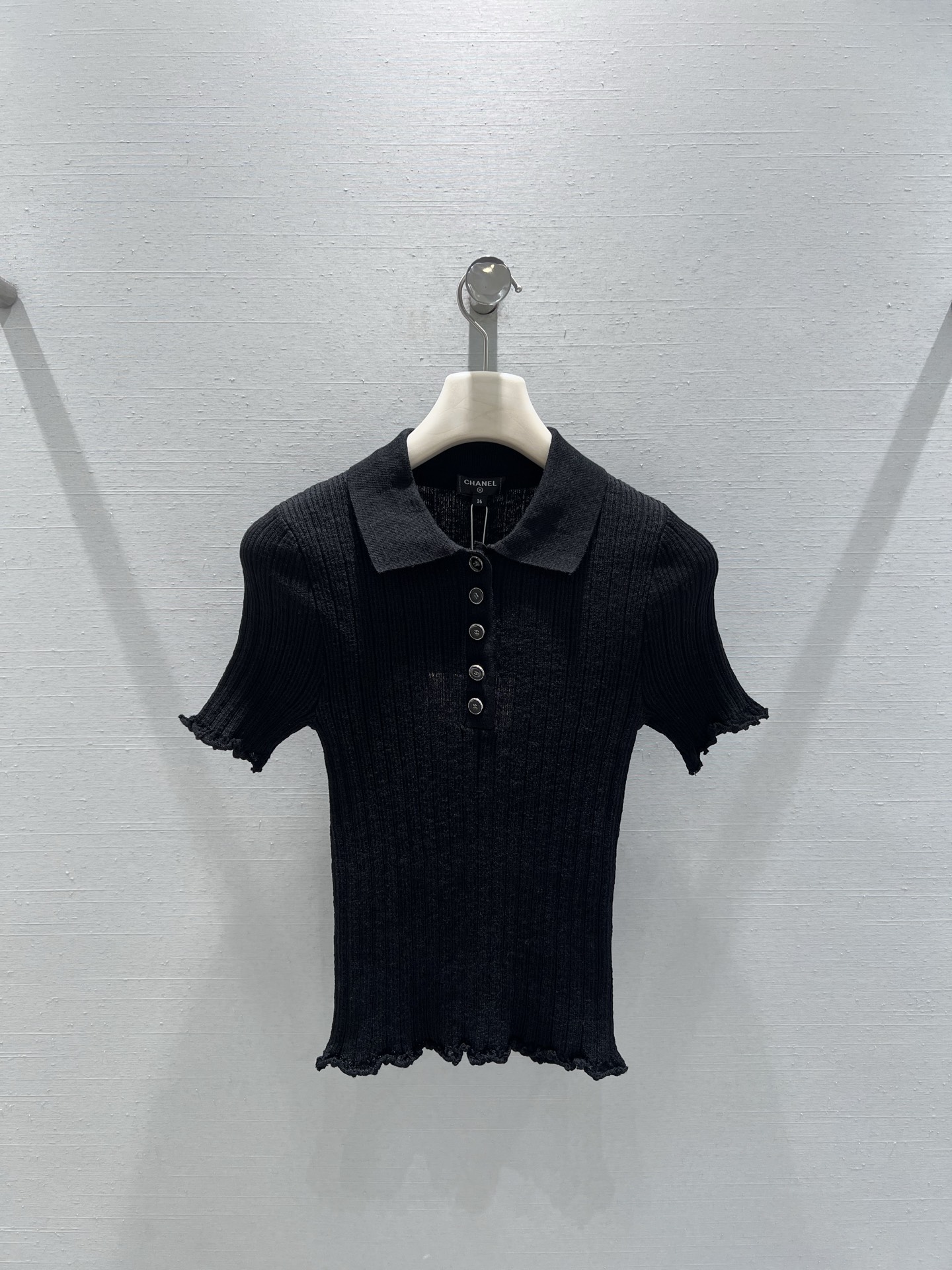 NO:736484,Support exchange Chan*L 2026SS early spring new product series //Polo collar knitted short-sleeved top is made of high-elastic vertical pit strip knitted fabric, which closely fits the body shape and can outline the beautiful waist and abdomen curve. The neckline retains the iconic button placket, and the ruffle design on the cuffs and hem breaks the dull feeling of pure black and adds a casual and lazy atmosphere. SML real shot details, chanel, T-shirt,19860909支持换款Chan*L 2026SS早春新品系列//Polo领针织短袖上衣采用高弹竖坑条针织面料,紧密贴合身形,能勾勒出优美的腰腹曲线.领口保留了标志性的纽扣门襟,袖口与衣摆的荷叶边设计打破了纯黑的沉闷感,增添一丝随性慵懒的氛围.SML实拍细节,,chanel,T-shirt,,Women's clothing