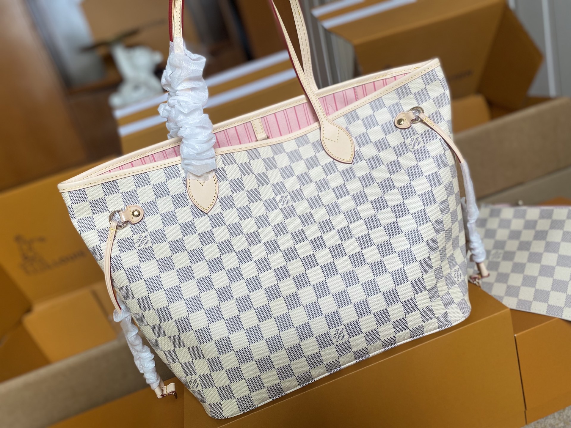 p450。 顶级原单 N41605 白格粉色新版新版本✨N41361 白格杏色 本款 Neverfull 中号手袋结合了经典设计与标志性细节。由清新 Damier Azur 帆布制成，采用多彩织物内衬，并搭配牛皮革饰边，宽敞却不臃肿。束紧两侧成就潮流风范，舒展即现休闲气质。配有纤薄手柄，可肩背或肘挎。可拆卸手袋可用作手拿包或口袋。
详细特征

31 x 28 x 14 厘米 
(长度 x 高 x 宽)

