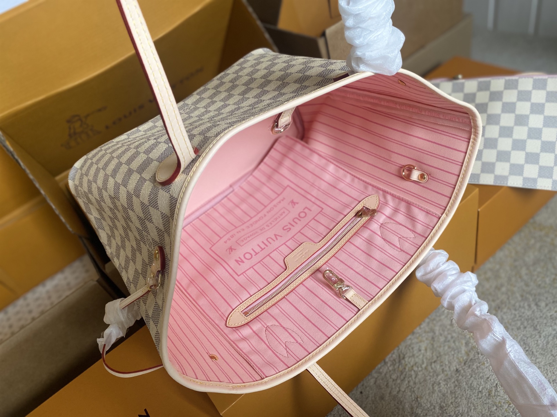 p450。 顶级原单 N41605 白格粉色新版新版本✨N41361 白格杏色 本款 Neverfull 中号手袋结合了经典设计与标志性细节。由清新 Damier Azur 帆布制成，采用多彩织物内衬，并搭配牛皮革饰边，宽敞却不臃肿。束紧两侧成就潮流风范，舒展即现休闲气质。配有纤薄手柄，可肩背或肘挎。可拆卸手袋可用作手拿包或口袋。
详细特征

31 x 28 x 14 厘米 
(长度 x 高 x 宽)
