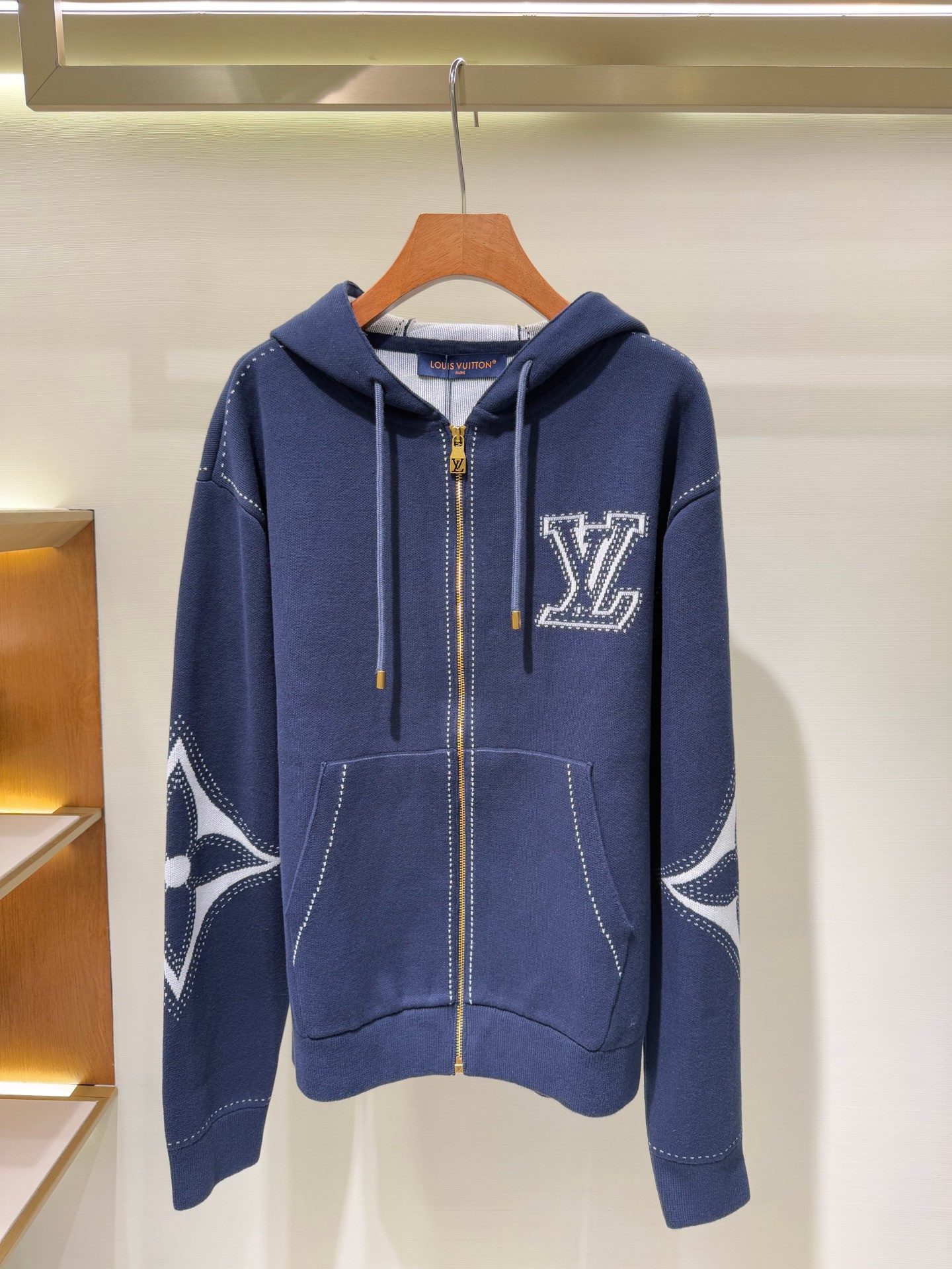 P245 Lv 蓝色针织嵌花手袖拉链连帽夹克外套 本款拉链棉质连帽衫为轻盈廓形织入繁复嵌花，兼具闲适风范与儒雅格调。正面和肘部分别呈现 LV 字母和大号 Monogram 花卉，虚线设计营造明线和刺绣观感，男女同款连帽外套。 面料：55%…