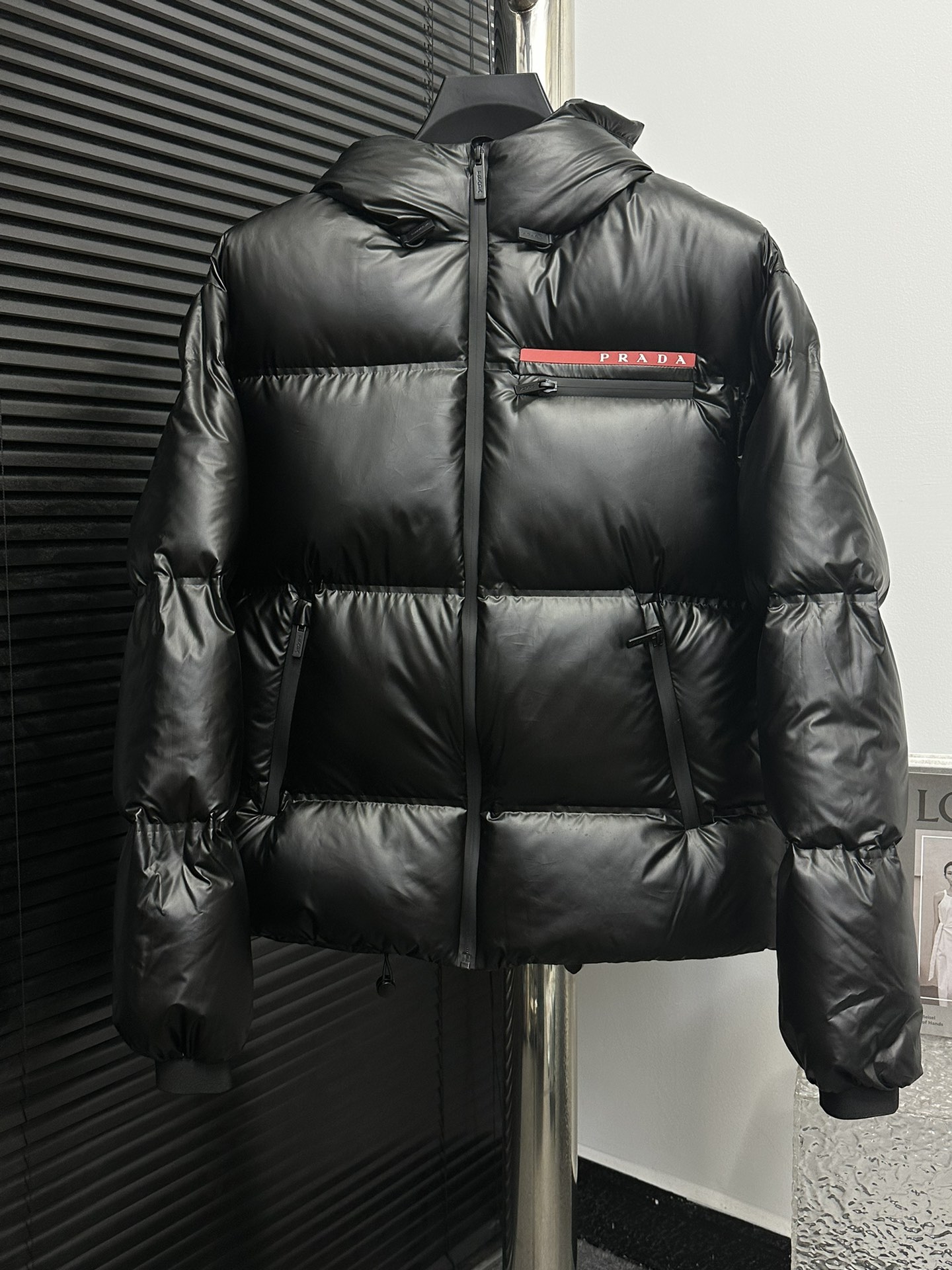 (Prada) La clásica chaqueta corta de plumón con etiqueta roja está confeccionada con tejidos de alta tecnología, como n…