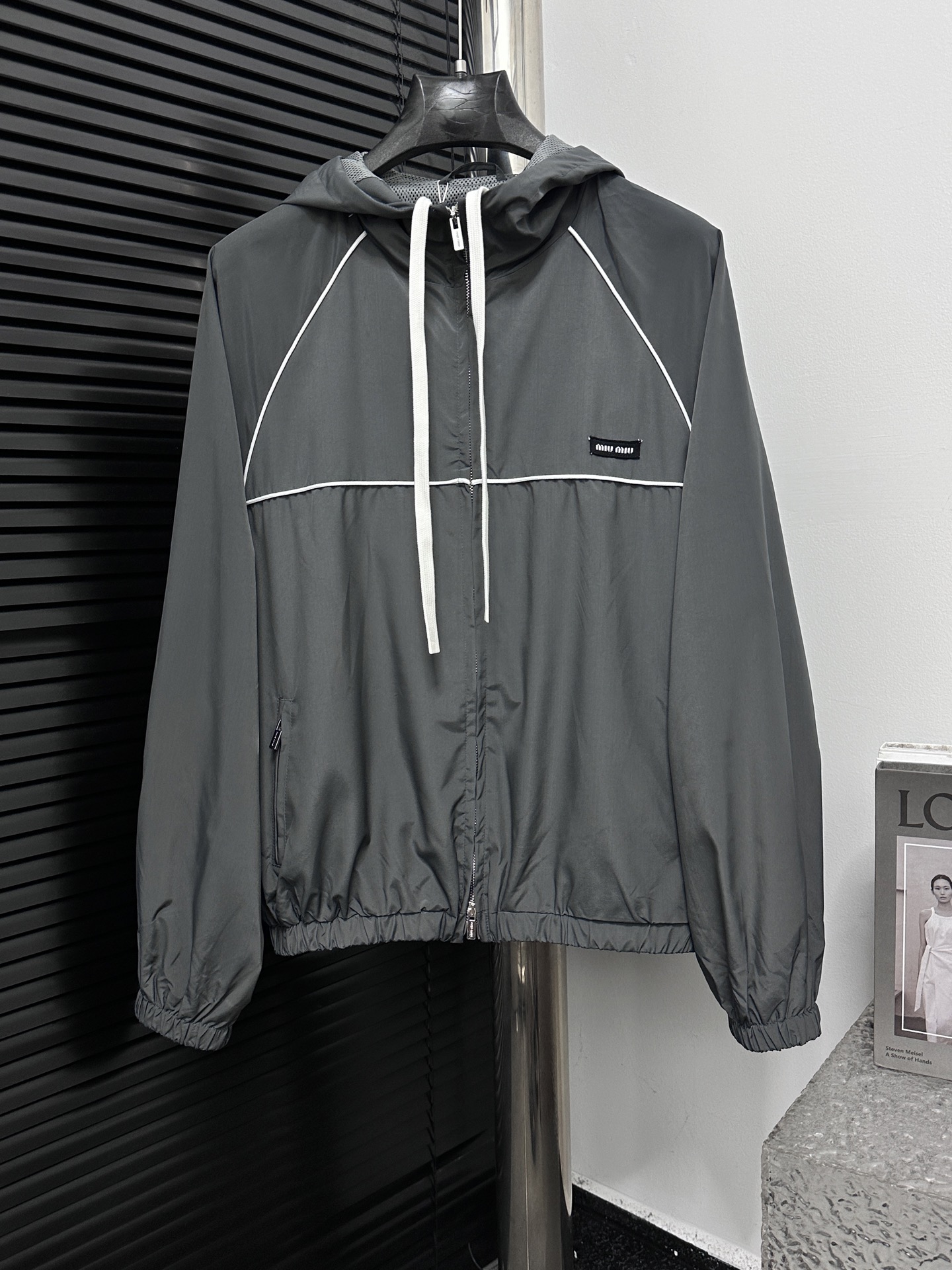 ￼ P225 【MIUMIU】缪缪 25SS拉链风帽夹克 定制冷萃智孔纤维尼龙精纺布 轻薄细腻 舒适贴肤 以铝银色为主色调 冷冽而迷人 采用进口专机红外线定位“Miu Miu 贴饰标签” 位置更为精准 牢固结实 模版机…