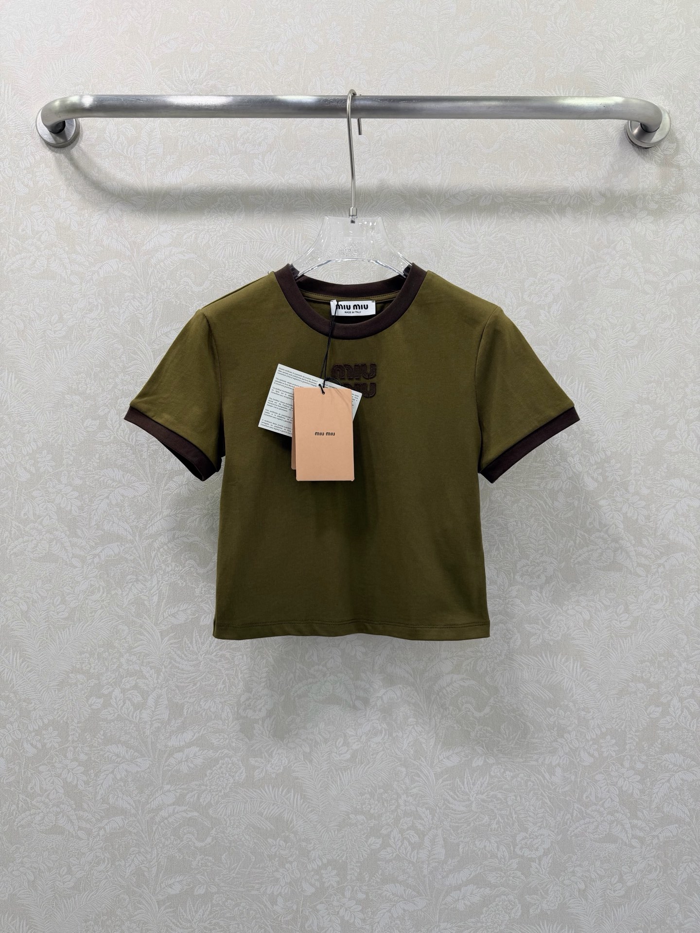 NO:721393,Miu Mi* 26Ss early spring new style, contrasting color round neck cotton short-sleeved T-shirt, top quality version!  The main tone is retro military green, with a brown contrasting round collar and cuffs, creating a sweet element that is highly recognizable to the brand. It is made of high-quality cotton fabric, which is soft and breathable to the touch and has excellent skin-friendliness; it is slim-fitting and fits the body shape, not tight and looks more neat. The chest has a three-dimensional Lo  go embroidery craftsmanship is exquisite, injecting light luxury texture into basic T-shirts. It is a versatile item for daily wear and styling in early spring. Available in stock SMLB, Miu Miu-clothing, miumiu, T-shirt, tees, t-shirt,19860909Miu Mi* 26Ss早春新款 撞色圆领棉质短袖T恤 顶级高版出品！以复古军绿为主调,搭配咖色撞色圆领与袖口,打造出极具品牌辨识度的甜美元素.精选优质棉质面料,触感柔软透气,亲肤性极佳；修身剪裁贴合身形,不紧绷更显利落.胸前立体logo刺绣工艺精致,为基础款T恤注入轻奢质感,是早春日常穿搭与造型搭配的百搭单品.现货发售SMLB,缪缪-服装,miumiu,T-shirt,tees，t-shirt,,Women's clothing