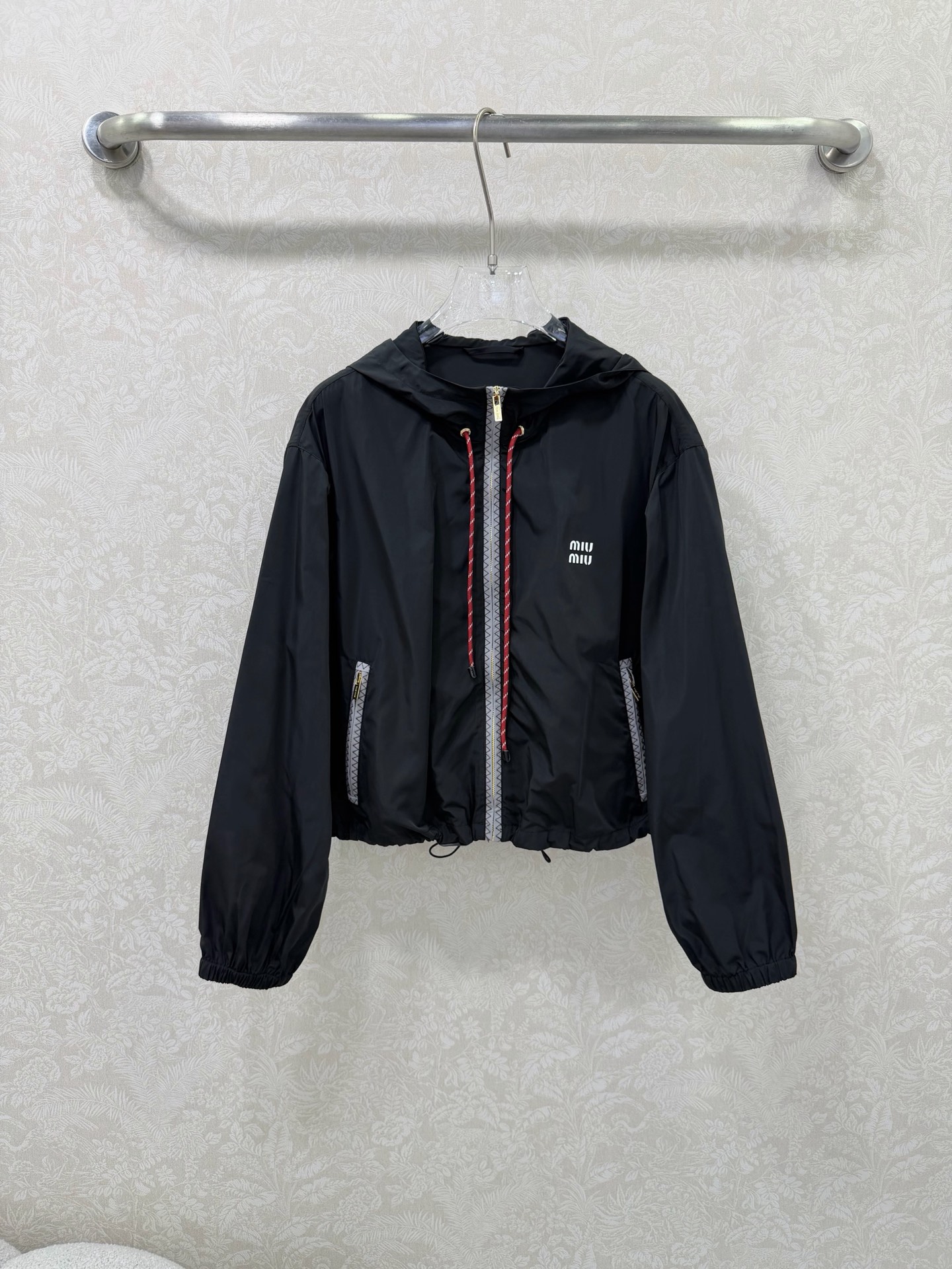 NO:744627,miumi*26 new side webbing hooded short sun protection jacket is an iconic item of miu style!  The placket and pocket edges are spliced with gray zigzag webbing, which extends the visual lines vertically, enhances the sense of sports and leisure, and improves recognition. The hood is equipped with contrasting drawstrings (blue and white drawstrings for the navy model, red and white drawstrings for the black model), adding a lively feel, and the shape of the hat can be freely adjusted. The front pocket is equipped with a gold zipper, which enhances the light luxury texture, is both practical and decorative, and is convenient for placing small items.  The short loose fit + hem drawstring design just falls on the waistline, optimizing body proportions, making you appear taller and slimmer; lantern sleeves + elastic cuff design create a casual and lazy atmosphere. The white 'miu mi*' letter logo is printed on the chest, low-key highlighting the style attribute, and the details are exquisite. 2 colors and 3 sizes SMLR, Miu Miu-clothing, miumiu, jackets & coats, hats,19860909miumi*26新款侧织带连帽短款防晒外套  miu系穿搭的标志性单品！门襟与口袋边缘拼接灰色锯齿纹织带,纵向延伸视觉线条,强化运动休闲感,同时提升辨识度.连帽处配有撞色抽绳（藏蓝款为蓝白抽绳,黑色款为红白抽绳）,增添活泼元气感,可自由调节帽型.前侧口袋配有金色拉链,提升轻奢质感,兼具实用性与装饰性,方便放置小物件. 短款宽松版型+下摆抽绳设计,刚好落在腰线位置,优化身材比例,显高又显瘦；灯笼袖+袖口松紧设计,营造随性慵懒氛围. 胸前印有白色“miu mi*”字母标识,低调点明风格属性,细节处尽显精致.2色3码SMLR,缪缪-服装,miumiu,jackets & coats,hats,,Women's clothing
