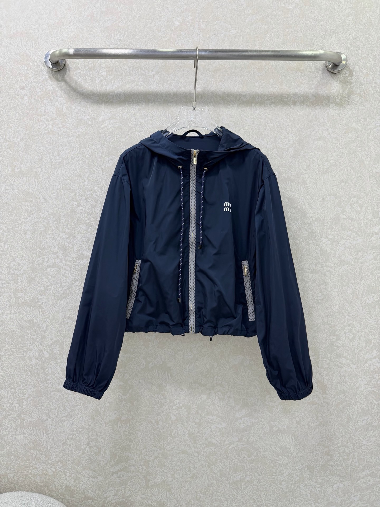 NO:744644,miumi*26 new side webbing hooded short sun protection jacket is an iconic item of miu style!  The placket and pocket edges are spliced with gray zigzag webbing, which extends the visual lines vertically, enhances the sense of sports and leisure, and improves recognition. The hood is equipped with contrasting drawstrings (blue and white drawstrings for the navy model, red and white drawstrings for the black model), adding a lively feel, and the shape of the hat can be freely adjusted. The front pocket is equipped with a gold zipper, which enhances the light luxury texture, is both practical and decorative, and is convenient for placing small items.  The short loose fit + hem drawstring design just falls on the waistline, optimizing body proportions, making you appear taller and slimmer; lantern sleeves + elastic cuff design create a casual and lazy atmosphere. The white 'miu mi*' letter logo is printed on the chest, low-key highlighting the style attribute, and the details are exquisite. 2 colors and 3 sizes SMLR, Miu Miu-clothing, miumiu, jackets & coats, hats,19860909miumi*26新款侧织带连帽短款防晒外套  miu系穿搭的标志性单品！门襟与口袋边缘拼接灰色锯齿纹织带,纵向延伸视觉线条,强化运动休闲感,同时提升辨识度.连帽处配有撞色抽绳（藏蓝款为蓝白抽绳,黑色款为红白抽绳）,增添活泼元气感,可自由调节帽型.前侧口袋配有金色拉链,提升轻奢质感,兼具实用性与装饰性,方便放置小物件. 短款宽松版型+下摆抽绳设计,刚好落在腰线位置,优化身材比例,显高又显瘦；灯笼袖+袖口松紧设计,营造随性慵懒氛围. 胸前印有白色“miu mi*”字母标识,低调点明风格属性,细节处尽显精致.2色3码SMLR,缪缪-服装,miumiu,jackets & coats,hats,,Women's clothing