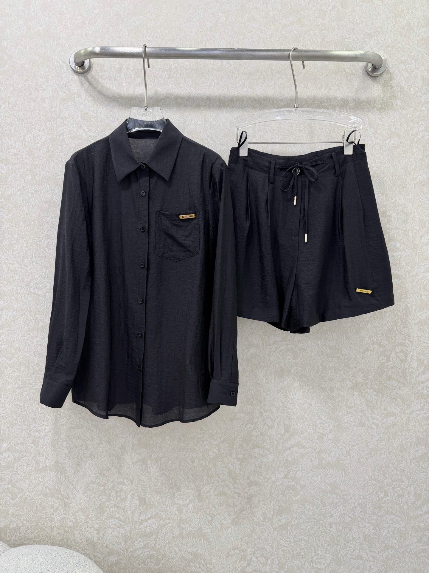 NO:744653,miumi*26 new suit shirt + shorts combination  With the exquisite miu gold label as the detail highlight, it is both capable and gentle, making it a versatile choice for spring and summer. The combination of a classic lapel shirt + high-waisted A-line shorts, with small gold labels on the left chest pocket and trousers, is low-key and noble, and enhances the overall look.  Body sophistication and recognition. The shirt is a loose and slightly off-the-shoulder version, which is not picky about your body shape, and is suitable for wearing alone or layered; the shorts are high-waisted with side ties, which effectively optimizes body proportions, making you appear taller and slimmer, while hiding the fat on your crotch and thighs!  2 colors and 3 codes SMLS, Miumiu-clothing, miumiu, shorts, shirts,19860909miumi*26新款套装 衬衫+短裤的组合 以精致miu金标为细节亮点,兼具干练与温柔感,是春夏换季的百搭选择.经典翻领衬衫+高腰A字短裤组合,左胸口袋与裤身均点缀金色小标,低调显贵,提升整体精致度与辨识度.衬衫为宽松微落肩版型,不挑身材,单穿或内搭都适配；短裤为高腰设计+侧边系带,有效优化身材比例,显高又显瘦,同时藏住胯部与大腿赘肉！2色3码SMLS,缪缪-服装,miumiu,shorts,shirts,,Women's clothing