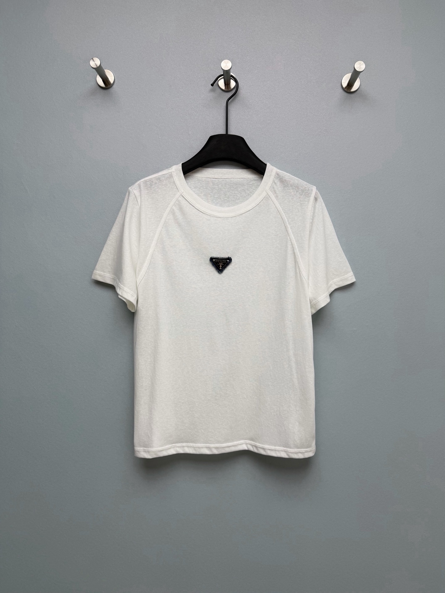 NO:755517,PRAD*26 new raglan sleeve triangle logo short-sleeved T-shirt. Raglan sleeves cut, modified shoulder line, can be worn with slippery/wide shoulders, slim and casual. Slightly permeable Tencel cotton fabric, very refreshing to wear in summer, with matte high-end feel, much better texture than ordinary white T. Black triangle logo on the chest, low-key and recognizable, full of light luxury, not exaggerated  The small and loose version is not flattering on your figure. It belongs to the brand's light luxury basic series. It combines minimalist design with iconic brand elements and is positioned as a high-end daily wear ~ Monochrome size 3 SMLR, Prada-clothing, prada, prada, T-shirt, tees, t-shirt,19860909PRAD*26新款插肩袖三角标短袖T恤.插肩袖剪裁,修饰肩线,溜肩/宽肩都能穿,显瘦又随性 微透天丝棉面料,夏天穿巨清爽,自带雾面高级感,比普通白T质感好太多 胸前黑色三角标,低调又有辨识度,轻奢感拉满,不浮夸 小宽松版型,不挑身材,属于品牌轻奢基础款系列,将极简设计与标志性品牌元素结合,定位高端日常穿搭～单色3码SMLR,普拉达-服装,prada,prada,T-shirt,tees，t-shirt,,Women's clothing