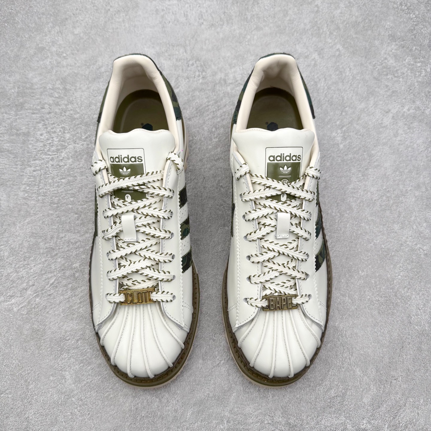 图片[2]-＃纯原 BAPE x CLOT x Superstar by EDISON CHEN 猿人头 凝结集团 陈冠希三方联名贝壳头KJ1473 以通体白色皮革材质和棕绿色鞋底线条打造，鞋面依旧是不对称鸳鸯的设计。鞋侧分别饰有BAPE STA Logo和阿迪达斯三条纹，搭配经典的Bape绿色迷彩图案和Clot中国风丝绸元素的压印标识呈现。鞋舌和鞋垫上上则分别点缀有CLOT x BAPE x 阿迪三方联名的标志，鞋带上也搭配金色CLOT和BAPE鞋带扣，后跟位置同样分别饰有BAPE和CLOT的品牌Logo，彰显特殊身份。实拍调校N版已经零色差零失真 百分百还原实物色彩所见即所得 不存在货不对板色差等低级问题 选购参考实物拍摄 不混卖不参货 只用心做好货严格选品 承诺混一赔十 尺码：36 36.5 37.5 38 38.5 39 40 40.5 41 42 42.5 43 44 44.5 45 46-选品中心