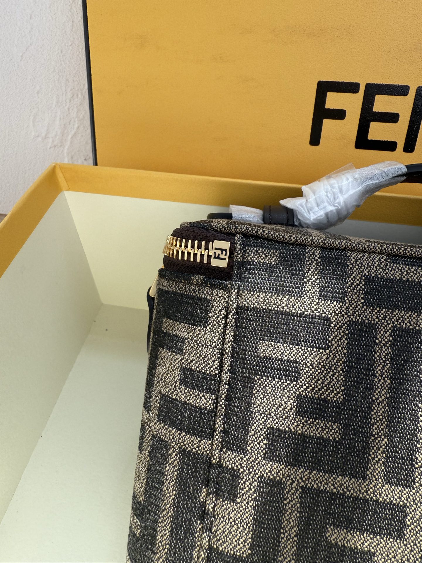 Fendi 廓形挺立的小巧型Vanity手袋采用双滑动拉链开合设计，饰有FF细节和皮革拉链头。烟草棕FF提花布料材质