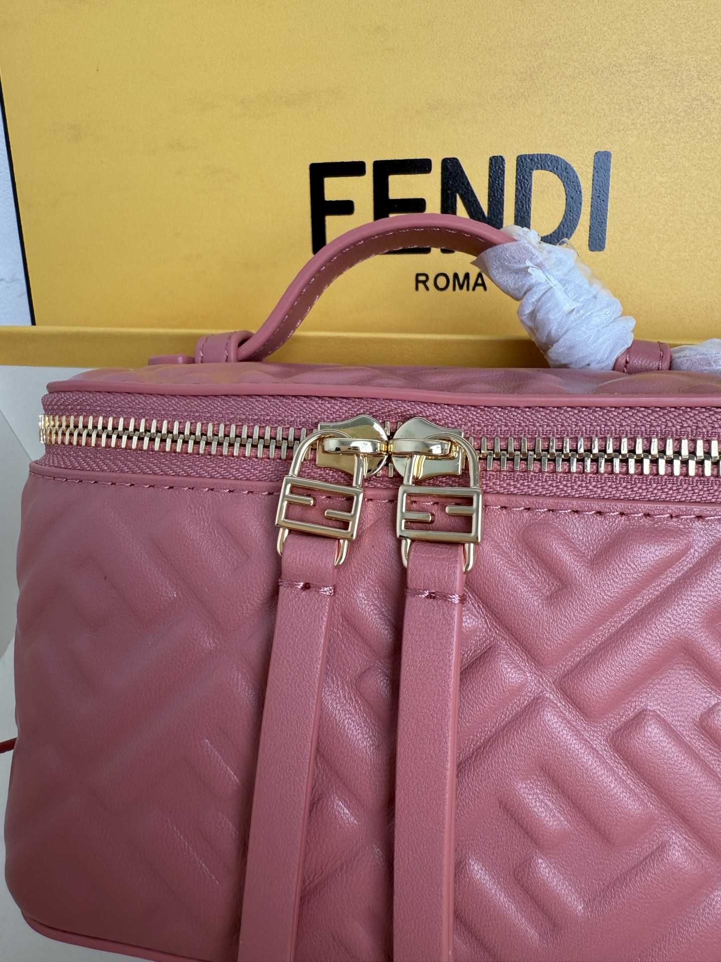 Fendi 廓形挺立的小巧型Vanity手袋采用双滑动拉链开合设计，饰有FF细节和皮革拉链头。烟草棕FF提花布料材质