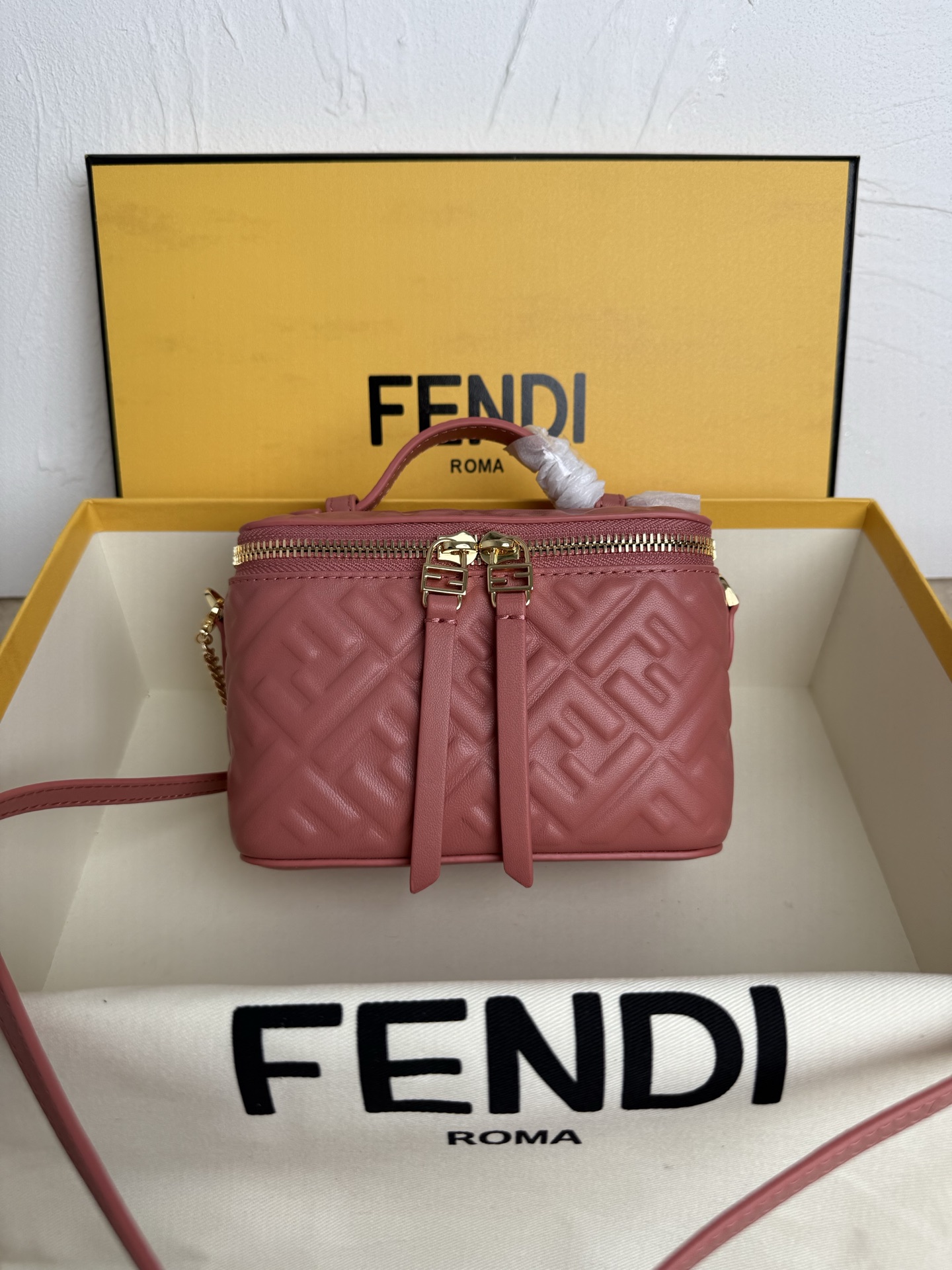 Fendi 廓形挺立的小巧型Vanity手袋采用双滑动拉链开合设计，饰有FF细节和皮革拉链头。烟草棕FF提花布料材质