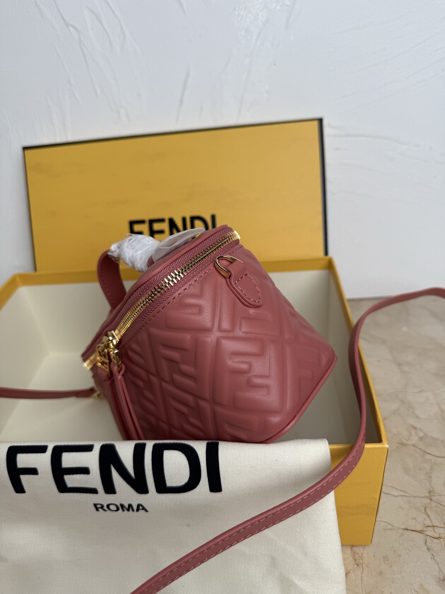 Fendi 廓形挺立的小巧型Vanity手袋采用双滑动拉链开合设计，饰有FF细节和皮革拉链头。烟草棕FF提花布料材质