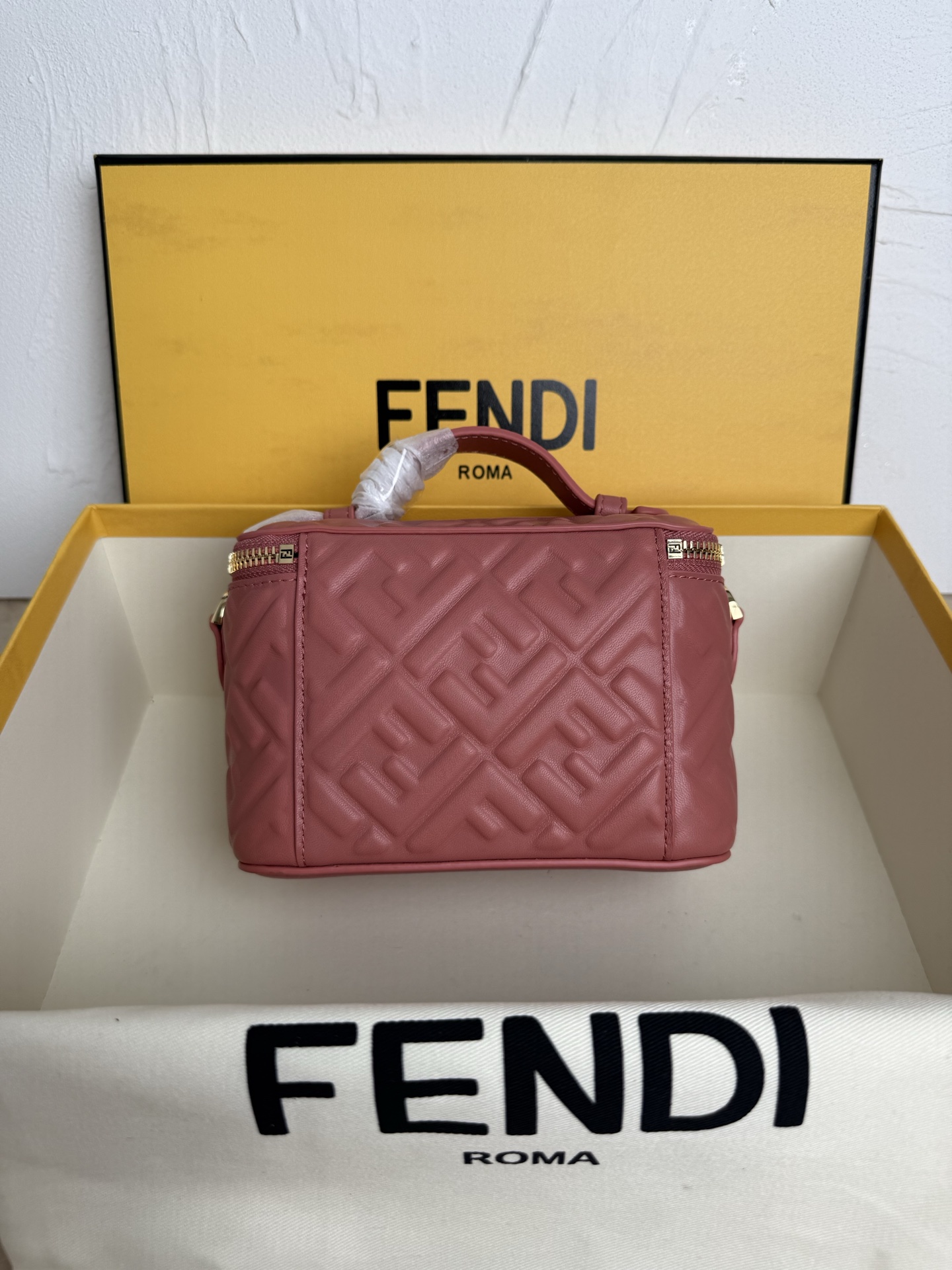 Fendi 廓形挺立的小巧型Vanity手袋采用双滑动拉链开合设计，饰有FF细节和皮革拉链头。烟草棕FF提花布料材质
