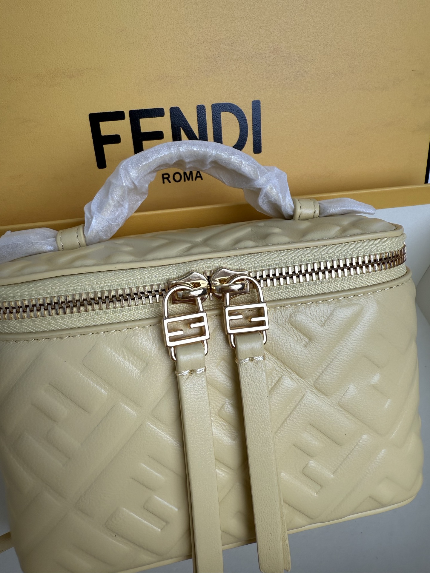 Fendi 廓形挺立的小巧型Vanity手袋采用双滑动拉链开合设计，饰有FF细节和皮革拉链头。烟草棕FF提花布料材质