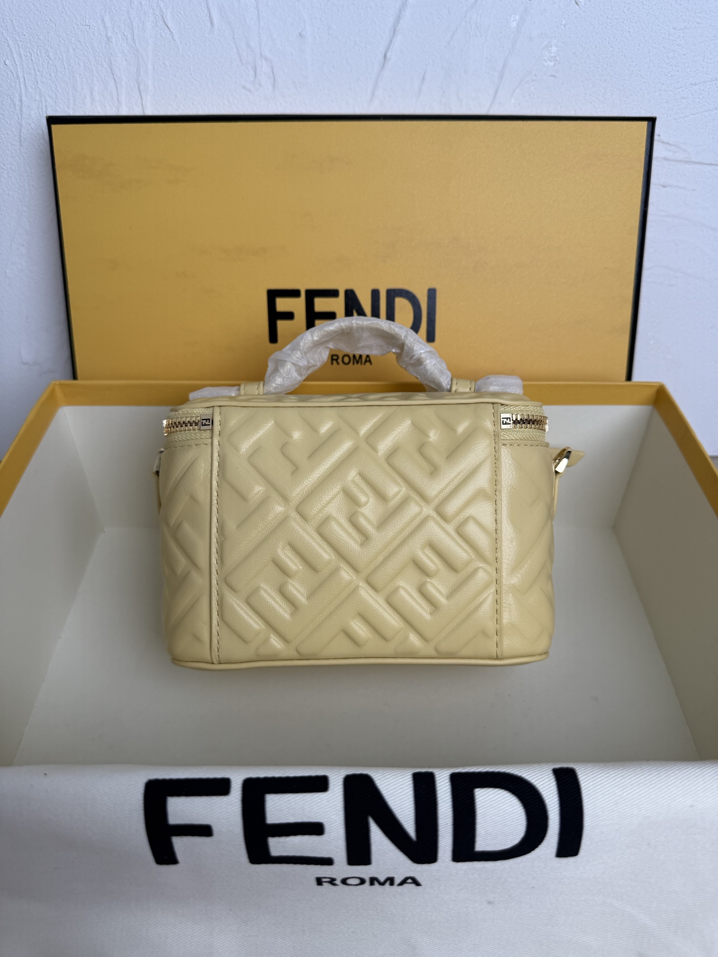 Fendi 廓形挺立的小巧型Vanity手袋采用双滑动拉链开合设计，饰有FF细节和皮革拉链头。烟草棕FF提花布料材质