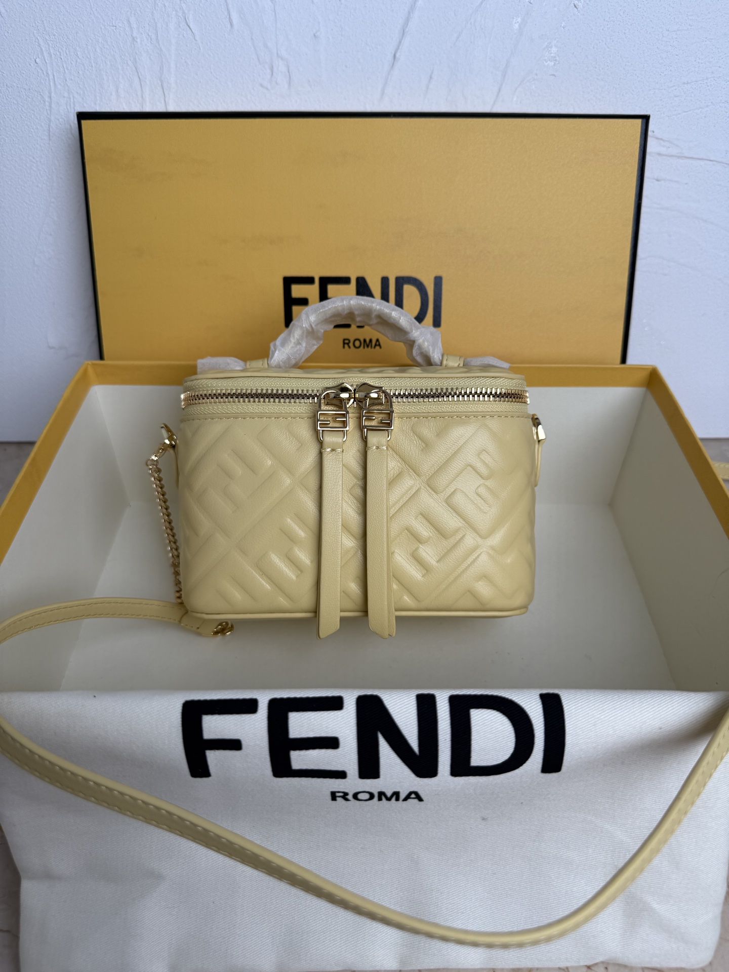 Fendi 廓形挺立的小巧型Vanity手袋采用双滑动拉链开合设计，饰有FF细节和皮革拉链头。烟草棕FF提花布料材质
