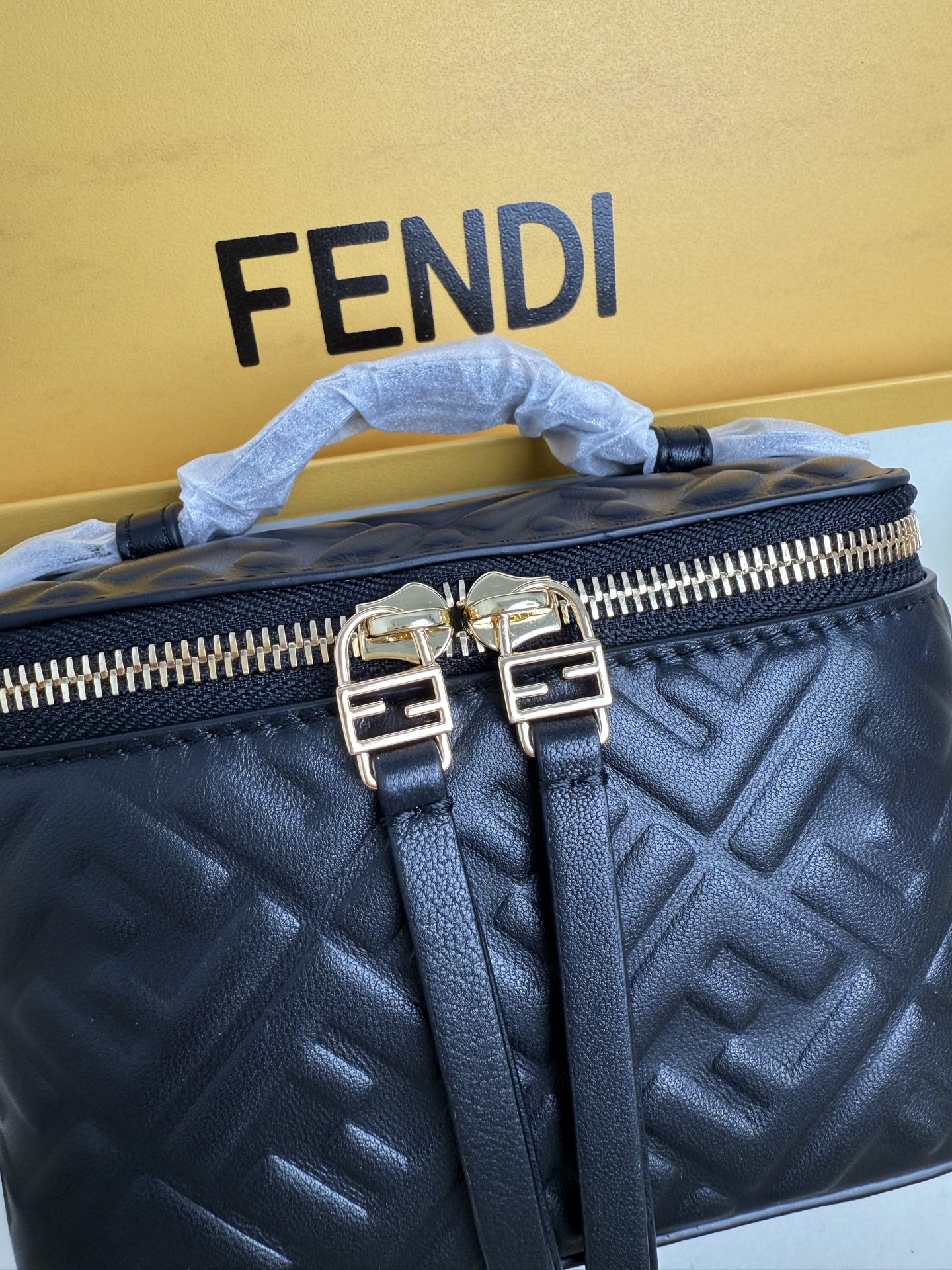 Fendi 廓形挺立的小巧型Vanity手袋采用双滑动拉链开合设计，饰有FF细节和皮革拉链头。烟草棕FF提花布料材质