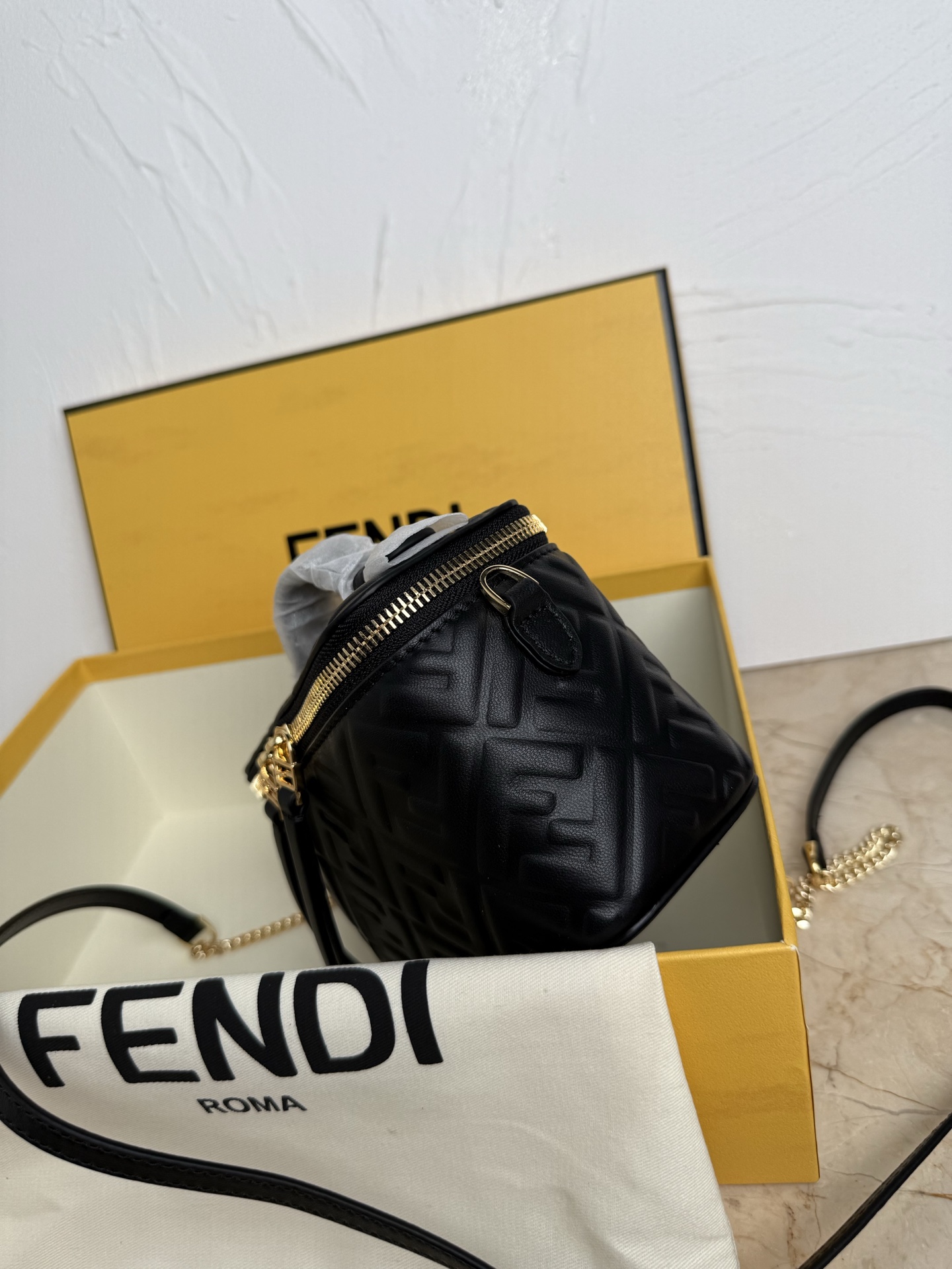Fendi 廓形挺立的小巧型Vanity手袋采用双滑动拉链开合设计，饰有FF细节和皮革拉链头。烟草棕FF提花布料材质