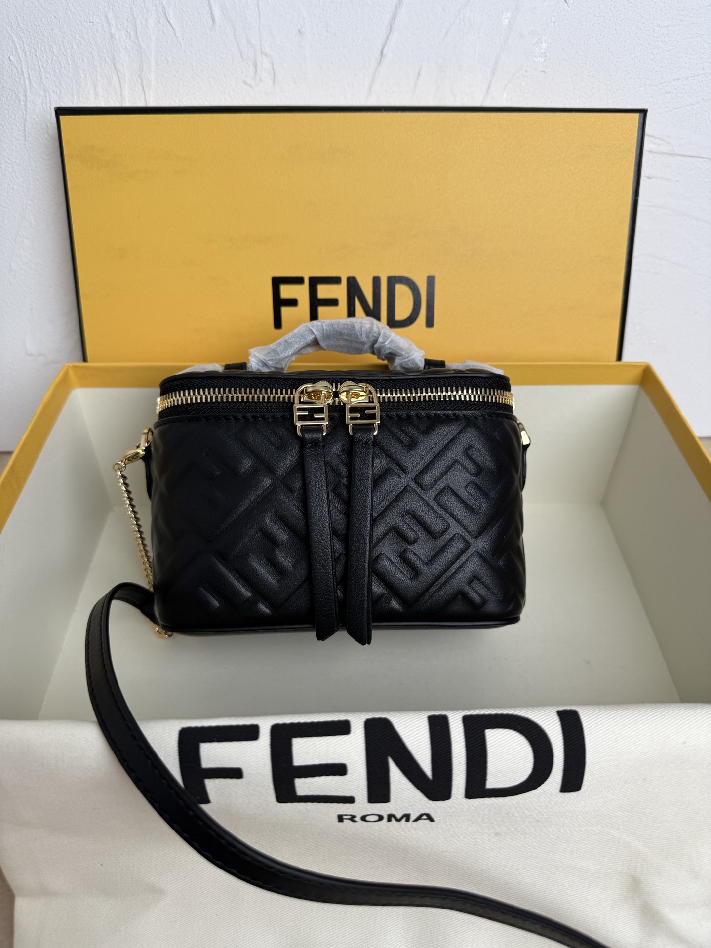 Fendi 廓形挺立的小巧型Vanity手袋采用双滑动拉链开合设计，饰有FF细节和皮革拉链头。烟草棕FF提花布料材质