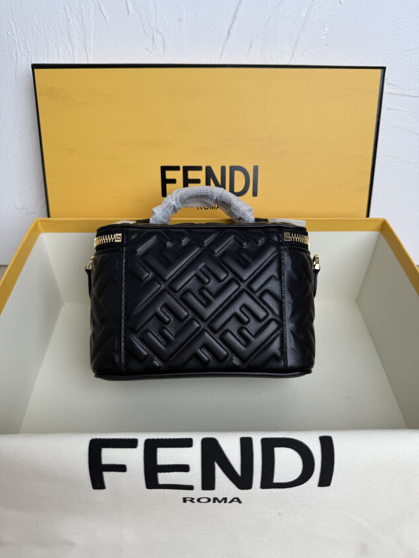 Fendi 廓形挺立的小巧型Vanity手袋采用双滑动拉链开合设计，饰有FF细节和皮革拉链头。烟草棕FF提花布料材质