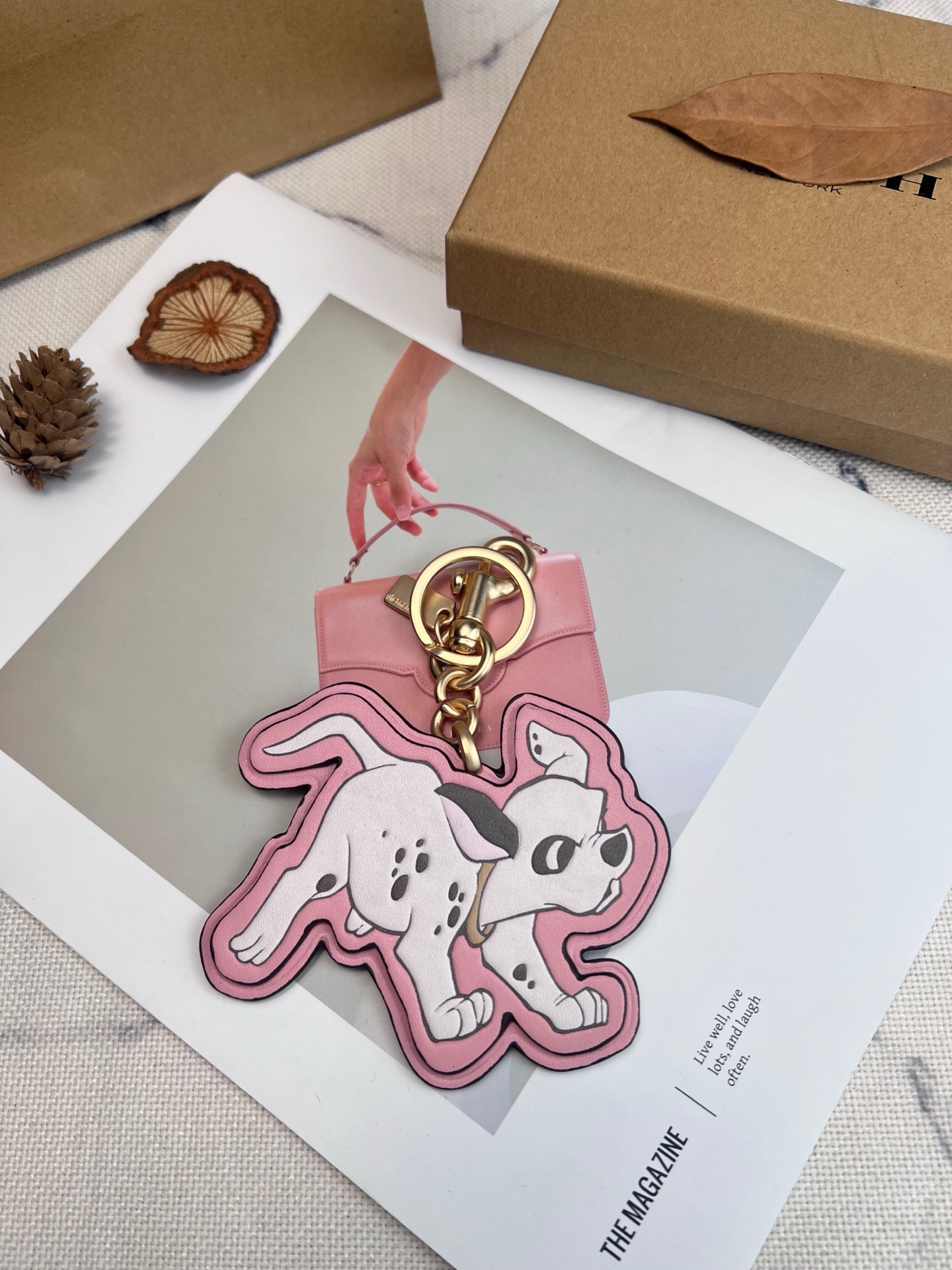 Coach x Disney联名斑点狗挂件，灵感来自《101忠狗》，皮革材质+粉色边框，少女感满满。金属五金连接，适合包包或钥匙扣，小巧可爱，收藏价值高，迪士尼粉丝必入!日常搭配或送礼都超合适门，组细节精致，兼具实用与趣味，出门也能萌趣加分~
尺寸11*9*1cm