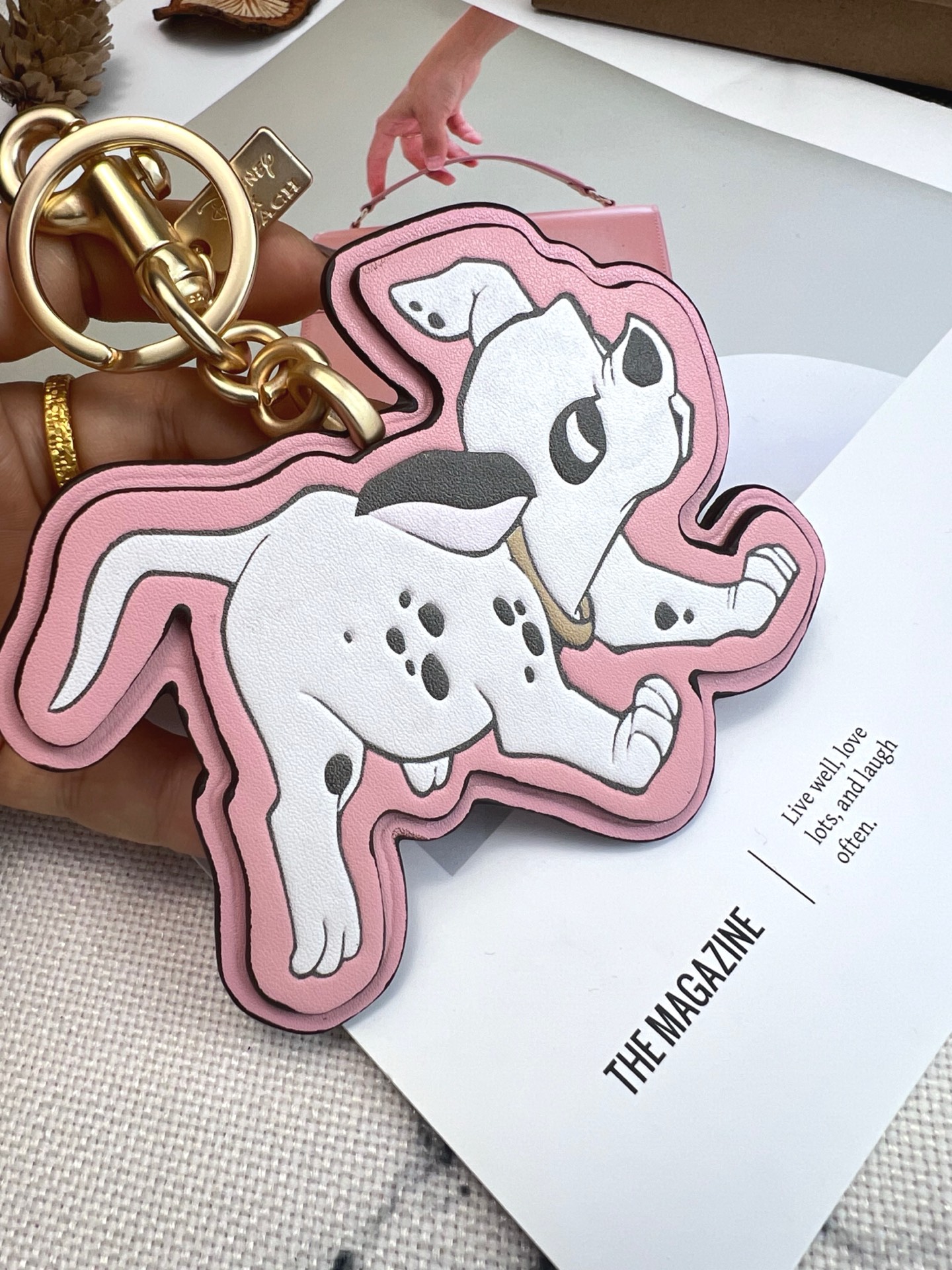 Coach x Disney联名斑点狗挂件，灵感来自《101忠狗》，皮革材质+粉色边框，少女感满满。金属五金连接，适合包包或钥匙扣，小巧可爱，收藏价值高，迪士尼粉丝必入!日常搭配或送礼都超合适门，组细节精致，兼具实用与趣味，出门也能萌趣加分~
尺寸11*9*1cm