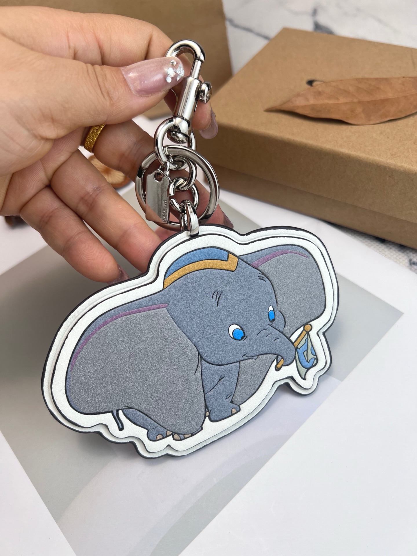 Coach x Disney联名的小飞象挂件，皮革材质+经典卡通造型，细节超还原!金属钥匙扣，包
包、钥匙都能挂，实用又可爱计。尺寸刚好，日常搭配无压力，迪士尼粉丝必收，送礼or自留都超合适，童心满满，收藏价值也很高哦!
尺寸8*12cm