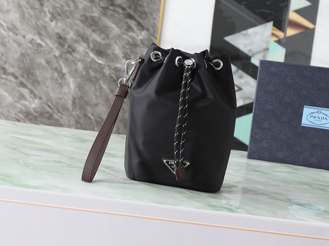 NO:719826,Top original quality with box Model 2NE067_2HE1_F0002 Color Black The drawstring bag is an iconic silhouette of the Prada collection, reinterpreted with technical details that inspire. Form and function, sporty and urban style meet, this Re-Nylon accessory, with leather wrist strap with technical cord drawstring and embellished with an enameled triangle logo. Removable wrist strap. Enameled triangle logo in metal.  .Drawstring closure. Lined. Width 15.5 cm, height 23 cm, length 10 cm. Prada [price based on quantity], prada, prada19860909顶级原单品质配盒子 型号2NE067_2HE1_F0002 颜色黑色 抽绳袋是Prada系列的标志性廓形,经过重新诠释,融入 启发的技术细节.形式与功能,运动与都市风格的邂逅,这款Re-Nylon配饰,配有皮革腕带,搭配技术绳抽绳,并饰有涂珐琅三角形金属徽标..可拆卸腕带 .涂珐琅三角形金属徽标 .抽绳开合.带衬里 宽度15.5厘米,高度23厘米,长度10厘米,普拉达【跑量价】,prada,prada,Bag