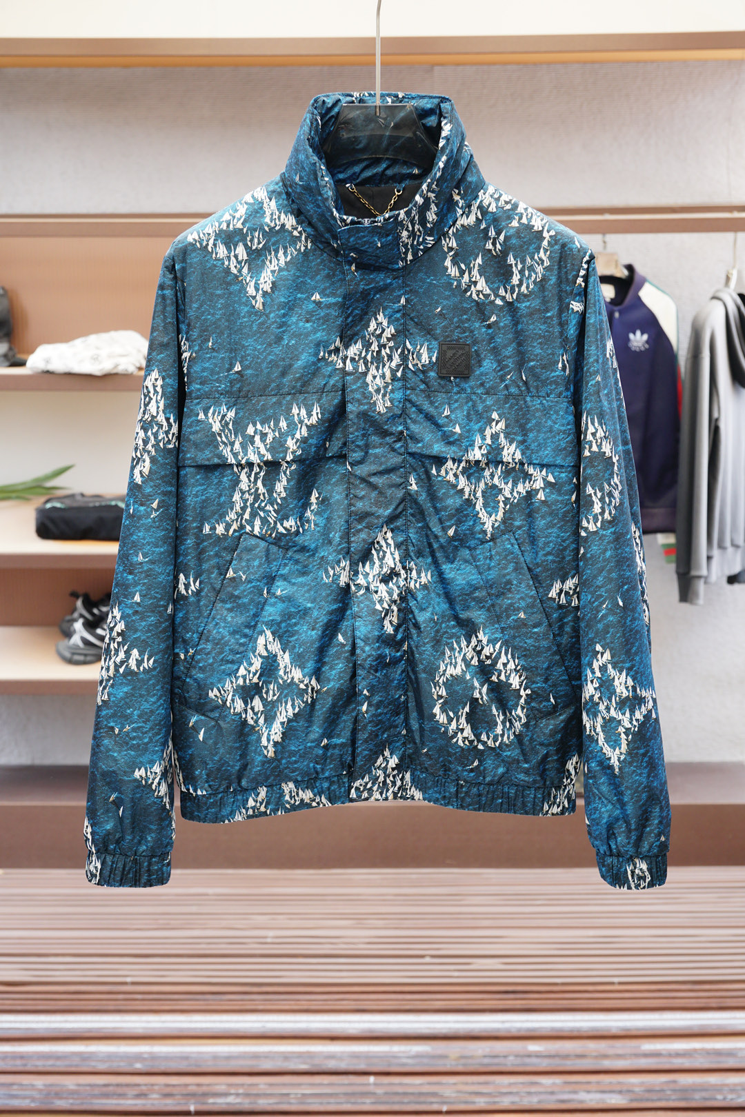 NO:521875,1.1 High-version, Product Introduction LV Louis Vuitton MONOGRAM Printed Windproof Jacket This windproof jacket is made of light and technological fabric, which uses patterns to depict the scene of the pocket fleet sailing on the blue water surface. Rubber patches embellish the chest and adjustable hood to facilitate the collar. The high-subscription tightly woven structure prevents cold air penetration, and has an additional water-spray coating on the surface, which has excellent tear resistance. Polyester fiber lining is suitable for pursuing light and quick-drying purposes, but it needs to weigh the balance between breathability and moisture absorption. The pattern is printed directly on the fabric through inkjet, supporting high-resolution complex patterns; the pattern penetrates the fiber inside, and the wear resistance is better than surface printing. The inside of the fabric may be composited with microporous coating, which achieves windproof and breathable balance through hot pressing.  Laser cutting is used in pockets, breathable zippers and other parts to avoid traditional sutures destroying the integrity of windproof. Three-dimensional cutting and splicing, multi-piece cutting design reduces sports constraints. Waist-closing design, hidden drawstring, balance function and daily wear.,,louis vuitton,louis vuitton,jackets & coats,hats,alexander wang198609091.1高版本,产品简介 LV 路易威登 MONOGRAM 印花防风夹克 本款防风夹克取材轻盈科技面料,以图案描摹袖珍船队于蔚蓝水面扬帆起航的情景.橡胶贴饰点缀胸前,可调节风帽方便收入衣领. 高支数紧密编织结构阻挡冷风渗透,表面附加防泼水涂层,抗撕裂性优异.聚酯纤维内衬适合追求轻便、快干的用途,但需权衡透气与吸湿的平衡. 通过喷墨方式将图案直接打印在面料上,支持高分辨率复杂图案；图案渗透纤维内部,耐磨性优于表面印刷.面料内侧可能复合微孔涂层,通过热压工艺实现防风透气平衡. 激光切割用于口袋、透气拉链等部位,避免传统缝线破坏防风整体性.立体裁剪拼接,多片式裁片设计减少运动束缚.收腰设计、隐藏式抽绳、平衡功能与日常穿搭.,,louis vuitton,louis vuitton,jackets & coats,hats,alexander wang,Men's clothing
