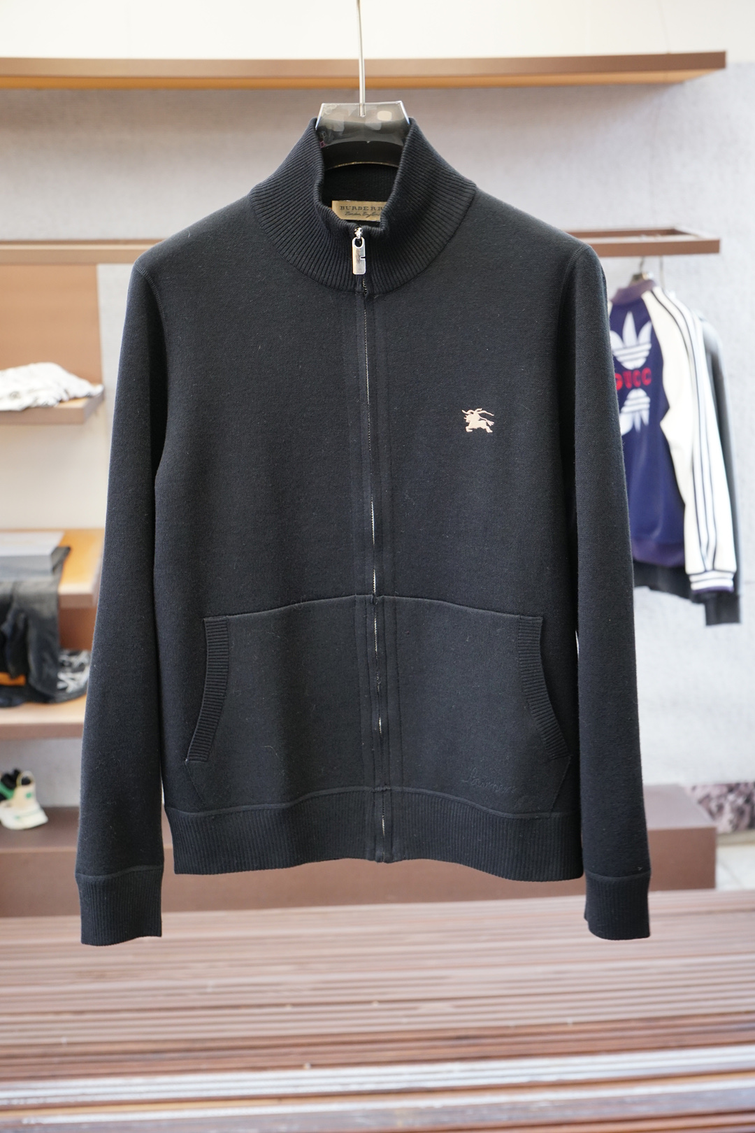 NO:566421,,BBR Burberry classic remodeling to keep out the cold] B's latest men's wool stand-collar jacket, channel of Shanghai trading company, one of the first choice items of major stars, exclusive sale!  Based on a century-old British aesthetics, this Burberry all-wool stand-up collar jacket injects the spirit of chivalry into contemporary wardrobes. Through six details, witness how luxury brands weave winter epics with wool. Logo system·Hidden secrets The golden logo on the left chest is presented with exquisite embroidery technology, forming a visual echo with the oval knight badge on the back. The classic knight totem contains the brand gene. The dynamics of the galloping horse and the arc of the flag fluttering are all accurately restored through embroidery in every inch.  All logos are in light gold color, forming a low-key luxury contrast with dark wool fabrics. Material language and warm philosophy. 70 wool blended fabrics present a delicate velvet feel, and high-count spinning ensures a balance of stiffness and softness. The black model highlights the cold temperament of the urban elite, while the dark blue model carries a British retro literary narrative.   Natural wool ripples can be seen on the surface of the fabric, creating a subtle flow of texture under light refraction. Functional aesthetics and refined dimensions. The smoothness of the custom metal zipper has been repeatedly tested, and the chamfered design of the puller avoids catching wool fibers. The stand-up collar structure adopts a double-layer reinforcement process to ensure windproofness of the neck while maintaining a three-dimensional outline. Morning meeting mode. The stand-up collar outlines a slender neckline. When paired with a white shirt, the golden logo is just faintly visible between the lapels of the suit. Weekend roaming mode  Wear alone with jeans, the knight badge and the leather handbag form a dialogue with retro elements. Night social mode. The dark blue model shows a subtle luster under the light, and the natural drape of wool creates a neat silhouette. Size selection: M-3XL, burberry, jeans, jackets & coats, shirts, business suit, alexander wang19860909,BBR巴宝莉经典重塑 御寒臻品】B家最新男士羊毛立领外套,上海贸易公司渠道,各大明星首选单品之一,独家销售！ 以百年英伦美学为基底,这款巴宝莉全羊毛立领外套将骑士精神注入当代衣橱.透过六处细节脉络,见证奢侈品牌如何用羊毛织就冬日史诗. 标志系统·暗藏玄机 左胸金色徽标以精美绣花工艺呈现,与背后椭圆形骑士徽章形成视觉呼应 经典骑士图腾蕴含品牌基因马匹奔腾的动态、旗帜飘扬的弧度,均在方寸之间通过刺绣精密还原 所有标识均采用浅金配色,与深色羊毛面料构成低调的奢华对比 材质语言·温暖哲学 70羊毛混纺面料呈现细腻绒感,高支数纺纱确保挺括度与柔软度的平衡 黑色款彰显都市精英的冷峻气质,深蓝款则带有英伦复古的文艺叙事 面料表面可见天然羊毛波纹,在光线折射下产生微妙的质感流动 机能美学·精工维度 定制金属拉链顺滑度经过反复测试,拉头倒角设计避免钩扯羊毛纤维 立领结构采用双层加固工艺,既保证脖颈防风性又维持立体轮廓 晨间会议模式 立领勾勒修长颈线,搭配白衬衫时金色徽标恰好在西装翻领间若隐若现 周末漫游模式 单穿搭配牛仔裤,骑士徽章与皮革手包形成复古元素对话 夜间社交模式 深蓝色款在灯光下浮现微妙光泽,羊毛天然垂坠感塑造利落剪影 码数选择:M-3XL,,burberry,jeans,jackets & coats,shirts,business suit,alexander wang,Men's clothing