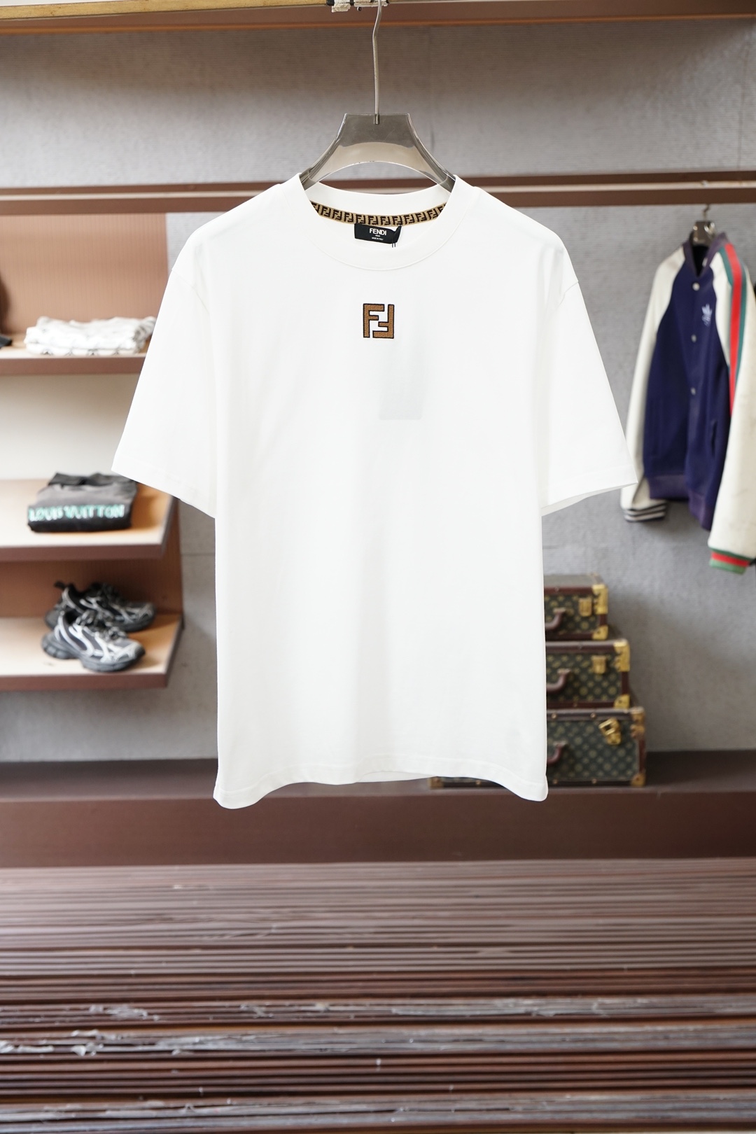 NO:733539,, Fendi (Fendi) white FF logo short-sleeved T-shirt is a classic light luxury basic model of the brand. The core features are as follows 1. The brand logo collar is edged with Fendi’s classic presbyopic webbing, and the brand’s iconic FF monogram badge is on the chest of the body. It is designed with a brown and black contrasting presbyopic pattern, which is highly recognizable and not exaggerated. 2.  The oversize version with loose shoulders and loose shoulders is suitable for many body shapes; the fabric is high-count combed cotton, which has both stiffness and breathability, and is the core material standard for luxury basic T-shirts. 3. Craftsmanship details The FF badge uses embroidery patch technology, with neat edges that are not easy to fall off; the collar is reinforced and hemmed to effectively avoid deformation after long-term wear, reflecting the brand's craftsmanship. 2. Brand and product positioning 1.  Design background The FF logo evolved from Fendi's iconic 'double F' presbyopia. After modern and simplified design, it has become the core visual symbol of the brand's youthfulness and trendiness, breaking the heavy feeling of traditional luxury goods. 2. The market attribute belongs to Fendi's entry-level light luxury items. It is a popular choice among fashion enthusiasts and entry-level consumers of luxury goods in China. It has both brand recognition and daily practicality. 3.  Style adaptation not only retains Fendi's high-end genes, but also can be perfectly integrated into various styles such as street, casual, light and trendy. It is a typical representative item of 'high luxury fashion branding'.,,fendi,fendi,versace,T-shirt,tees,t-shirt,19860909,Fendi（芬迪） 白色FF标识短袖T恤,属于品牌经典轻奢基础款,核心特征如下 1. 品牌标识领口内侧有芬迪经典的老花织带包边,衣身胸口位置是品牌标志性的FF字母组合徽章,采用棕黑撞色的老花图案拼接设计,辨识度极高且不浮夸. 2. 版型与面料宽松落肩的Oversize版型,适配多身形；面料为高支精梳纯棉,挺括度与透气性兼顾,是奢侈品基础款T恤的核心用料标准. 3. 工艺细节FF徽章采用刺绣贴布工艺,边缘工整不易脱落；领口做了加固包边处理,有效避免久穿变形,体现品牌工艺水准. 二、品牌与产品定位 1. 设计背景FF标识由芬迪标志性的“双F”老花演变而来,经现代简约化设计后,成为品牌年轻化、潮牌化的核心视觉符号,打破了传统奢侈品的厚重感. 2. 市场属性属于芬迪入门级轻奢单品,国内专是潮流爱好者与奢侈品入门消费者的热门选择,兼具品牌辨识度与日常实用性. 3. 风格适配既保留了芬迪的高端基因,又能完美融入街头、休闲、轻潮等多种穿搭风格,是“高奢潮牌化”的典型代表单品.,,fendi,fendi,versace,T-shirt,tees，t-shirt,,Men's clothing