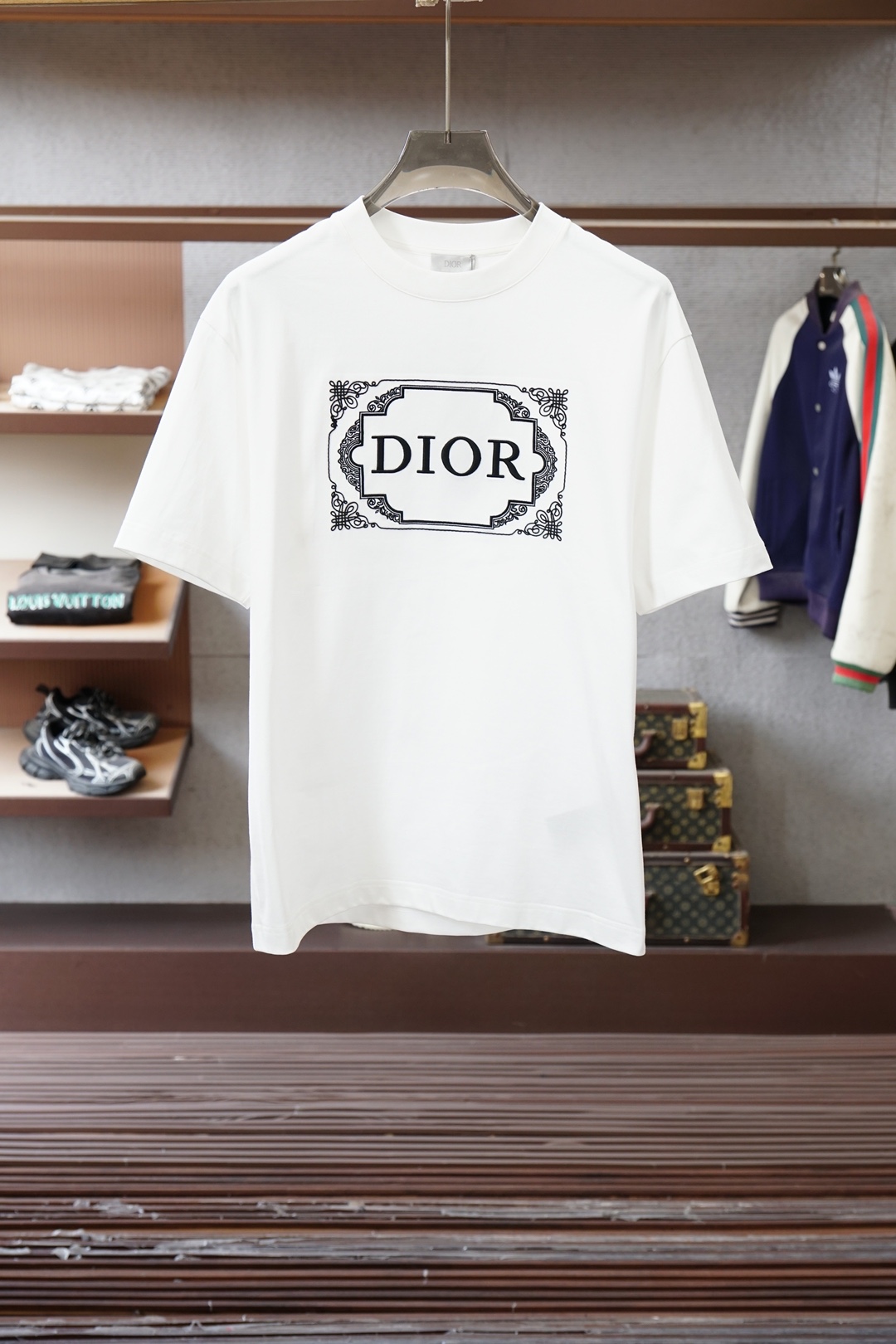 NO:733569,Dior's white retro pattern frame printed short-sleeved T-shirt is a brand's light luxury trend line item. The core features are as follows: 1. The design logo uses a black retro pattern frame to wrap the word 'DIOR' on the front of the body. The pattern details are exquisite, combining the brand logo with classical decorative aesthetics, with both recognition and artistic sense. 2.  The version and fabric adopt loose oversize with dropped shoulders; loose, fashionable and generous, dior, dior, versace, T-shirt, tees, t-shirt,19860909Dior（迪奥） 白色复古花纹边框印花短袖T恤,属于品牌轻奢潮流线单品,核心特征如下 1. 设计标识衣身正面采用黑色复古花纹边框包裹“DIOR”字样,花纹细节精致,将品牌标识与古典装饰美学结合,兼具辨识度与艺术感. 2. 版型与面料采用宽松落肩的Oversize；宽松时尚大方,,dior,dior,versace,T-shirt,tees，t-shirt,,Men's clothing